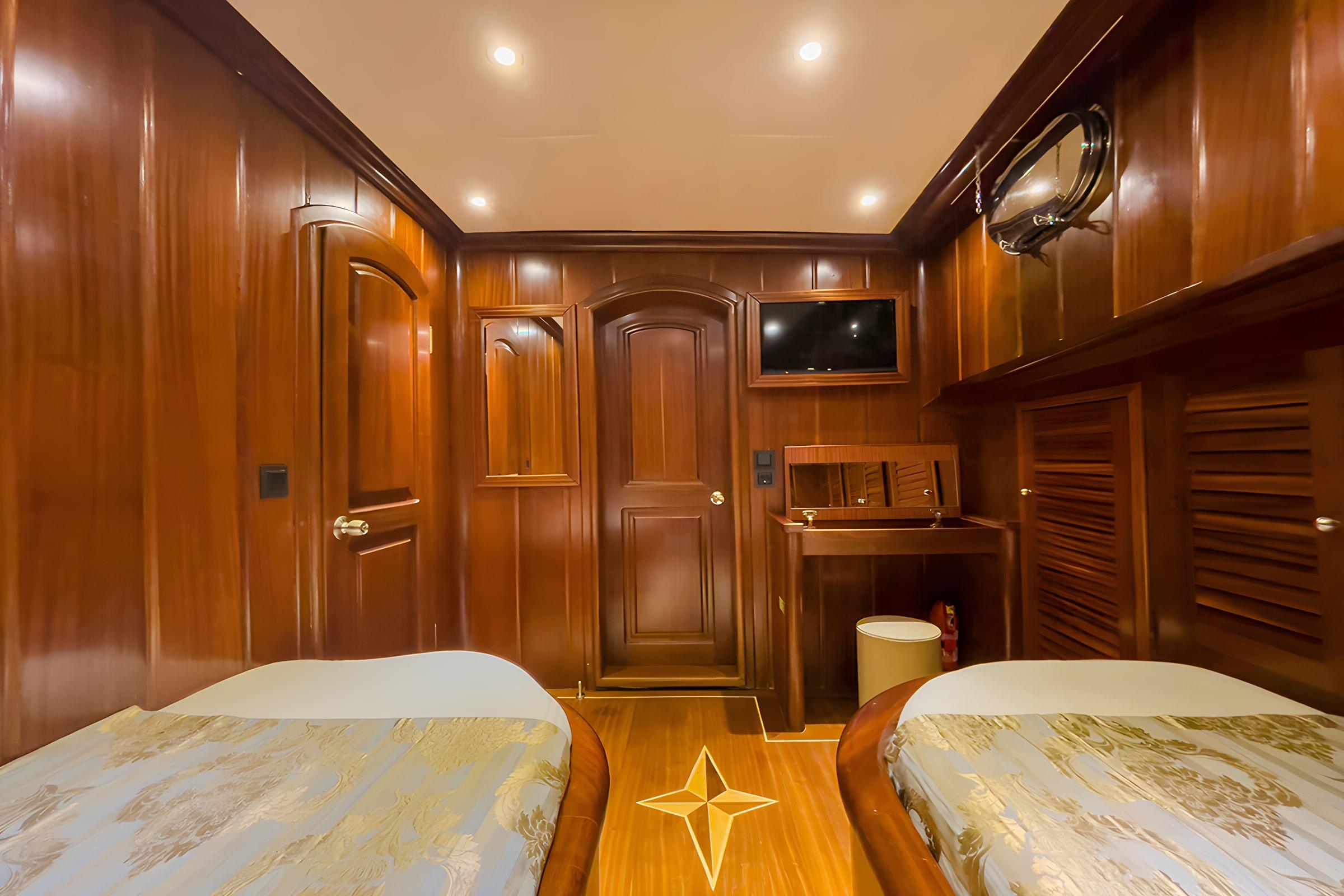 yacht twin cabin with two single beds, rich wood paneling and entertainment center