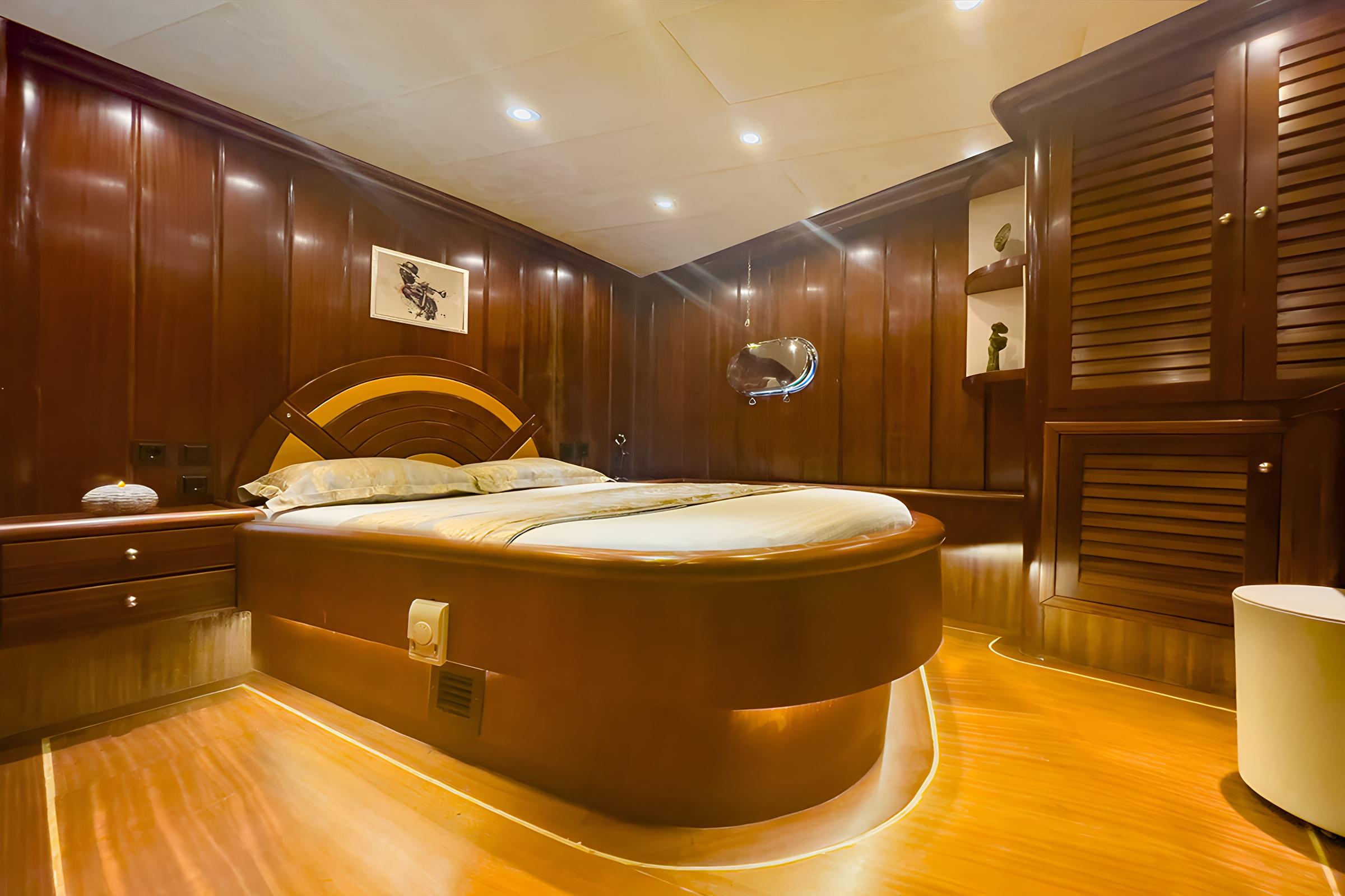 luxury yacht master cabin featuring circular bed with curved headboard and mahogany wood interior