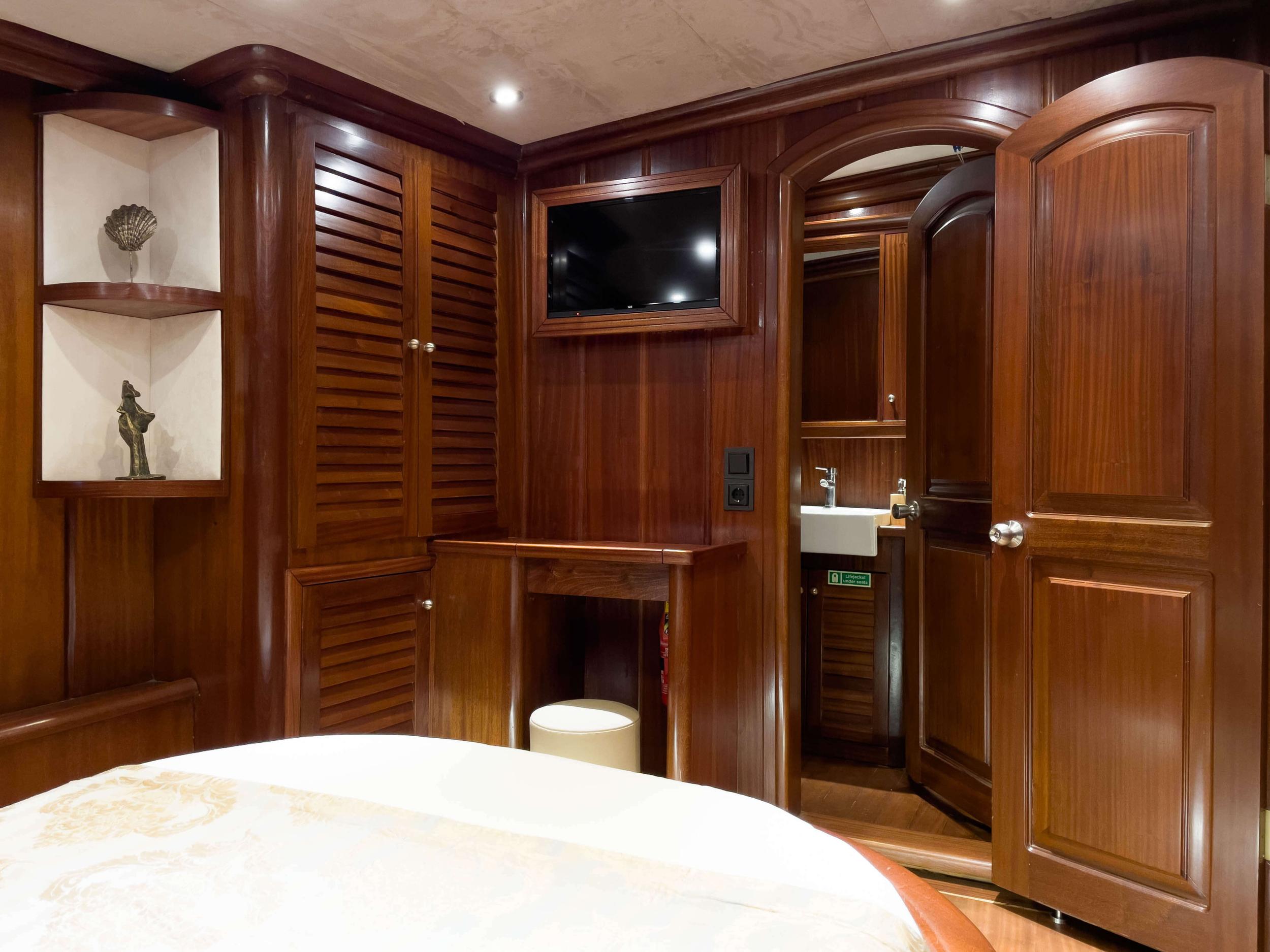 yacht cabin with wooden paneling, bed, built-in storage and en-suite bathroom door