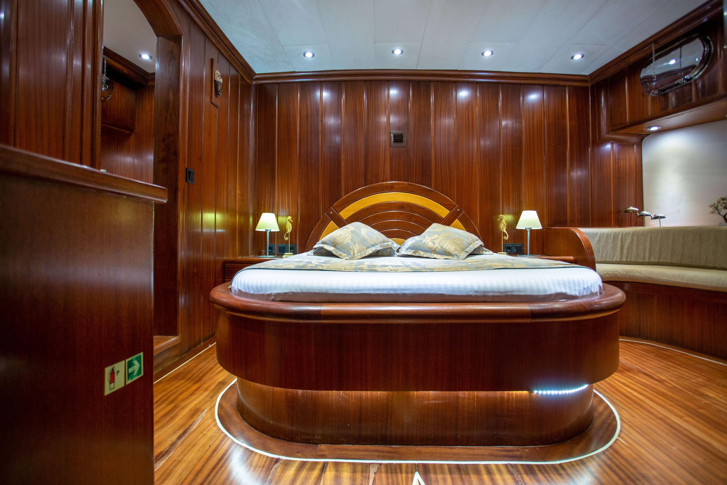 luxurious yacht master cabin featuring circular bed with curved headboard and mahogany woodwork