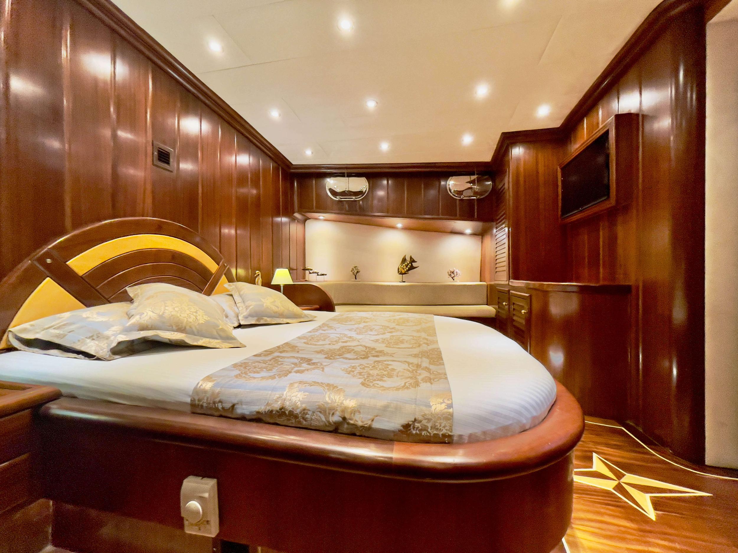 luxury yacht master cabin featuring circular bed with ornate bedding and rich mahogany wood paneling