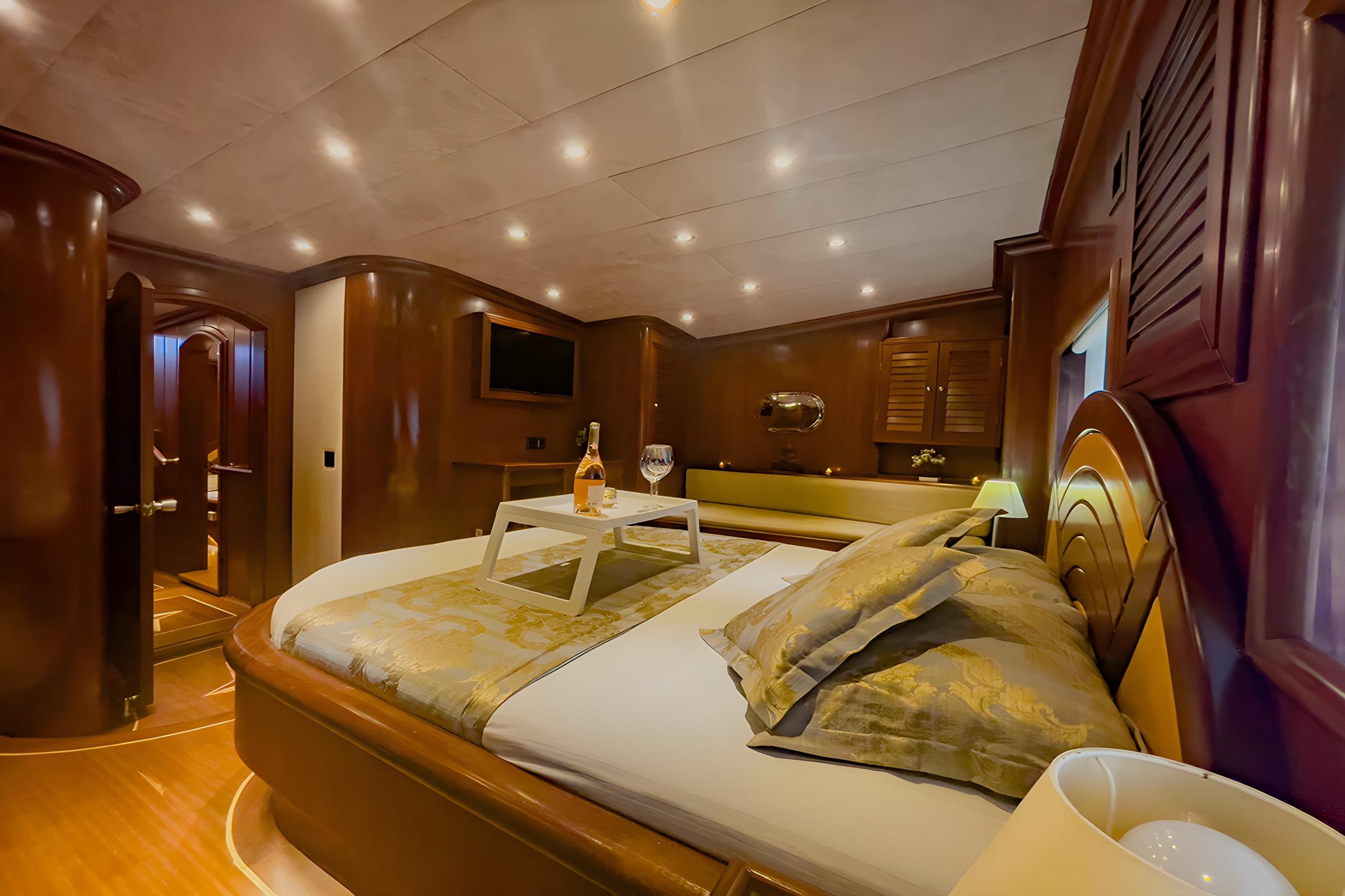 Master cabin with king bed, wooden paneling, recessed lighting and ensuite bathroom entrance