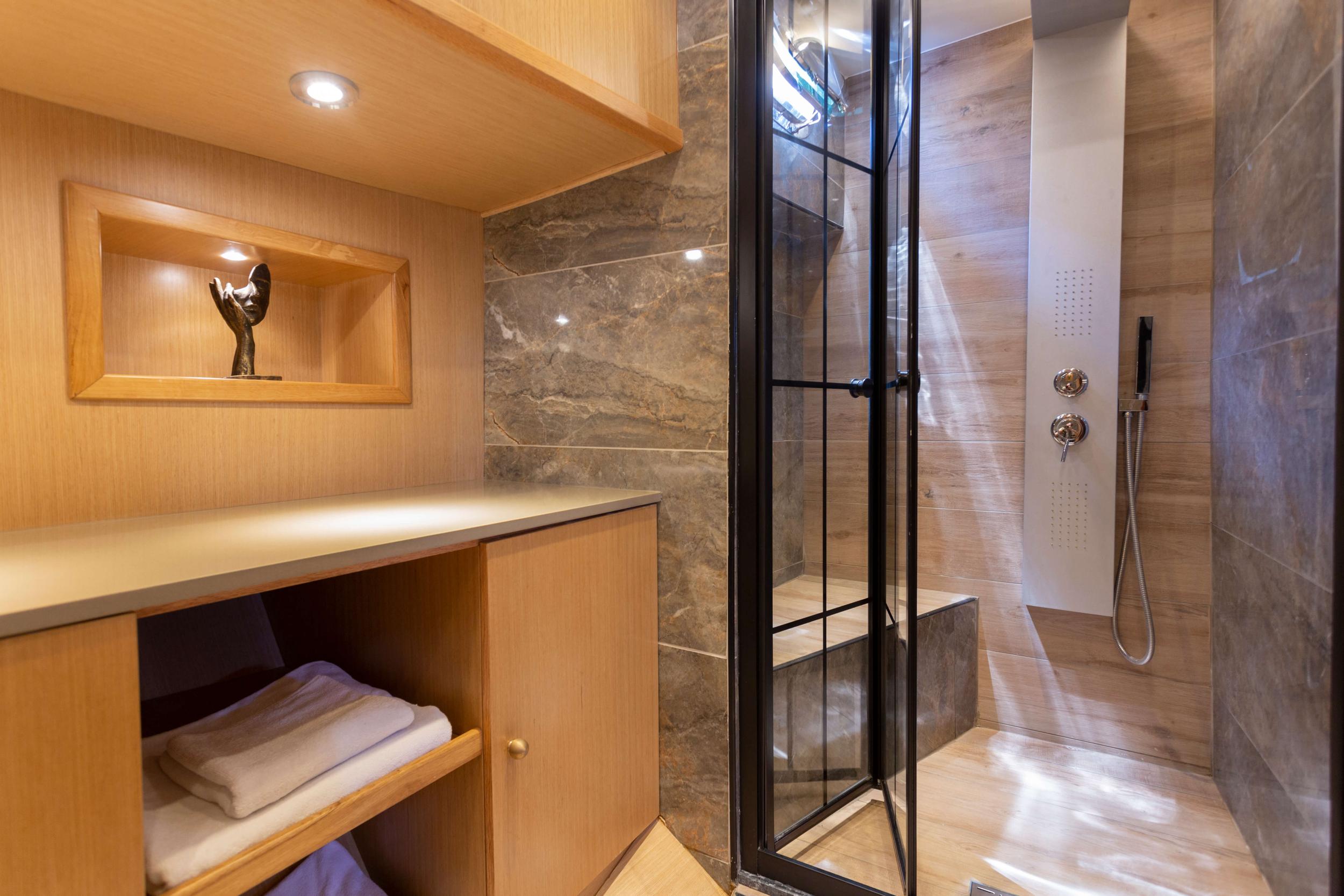luxury yacht bathroom with marble shower enclosure, wood vanity counter and built-in storage