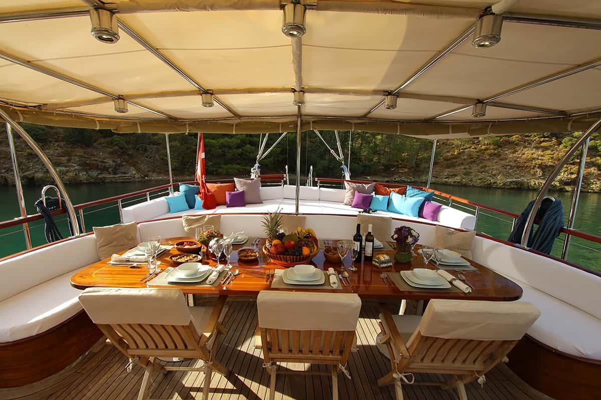 yacht aft deck dining area with set table featuring food, wine bottles and place settings