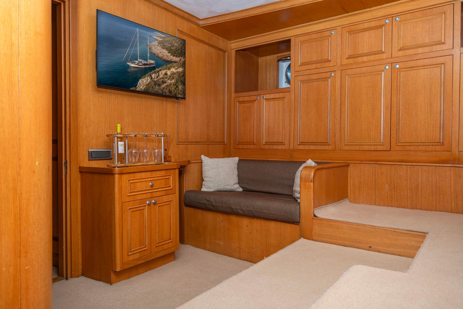 onboard cinema room with large wall-mounted TV, built-in seating and storage cabinetry