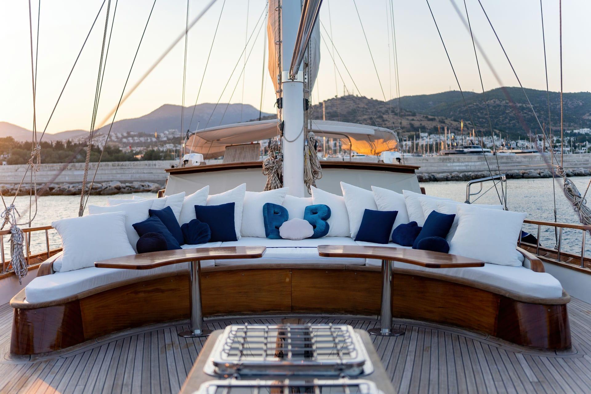 curved banquette seating with white cushions and navy pillows surrounding outdoor dining table on yacht deck