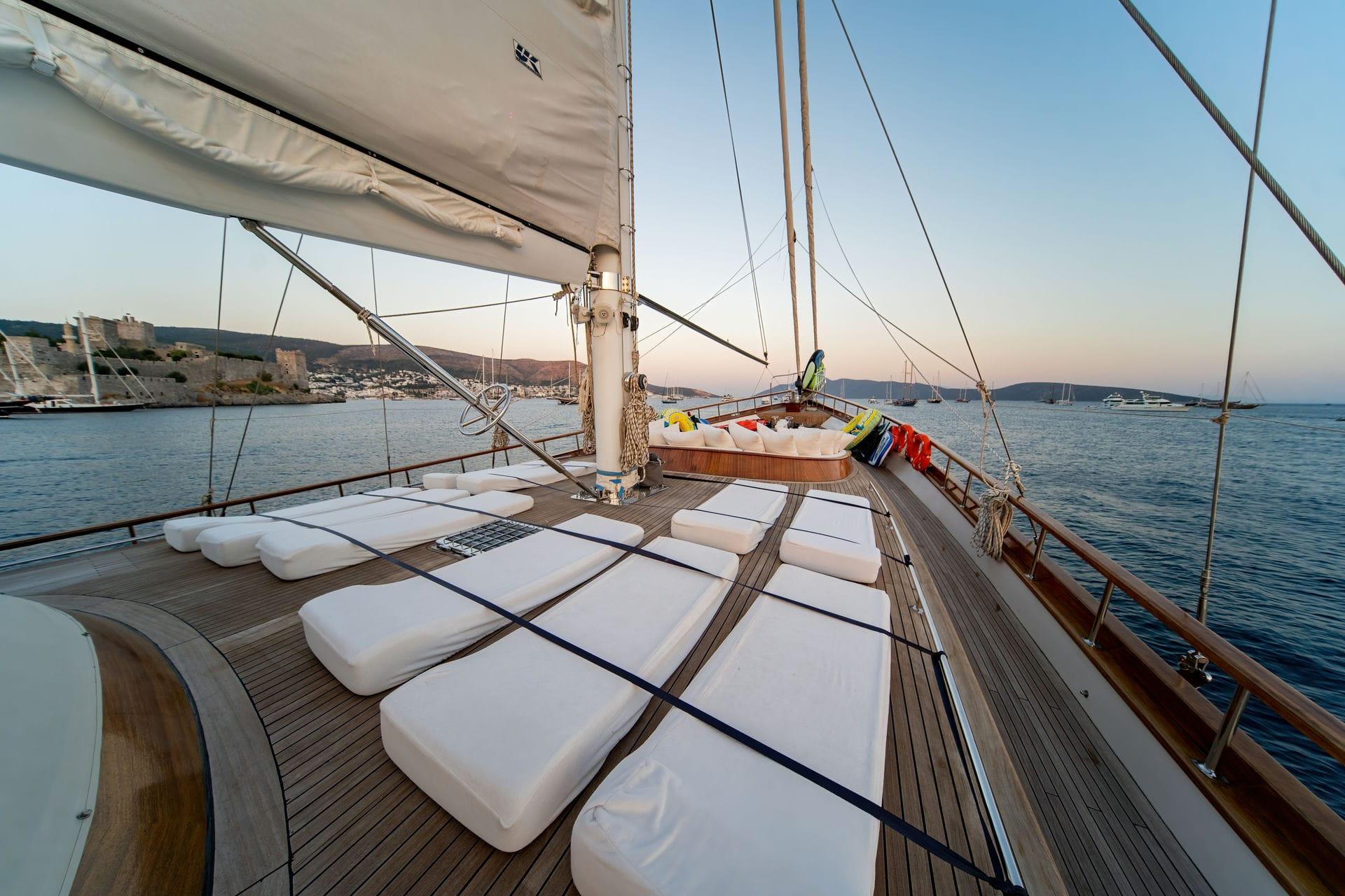 Gulet bow deck with white cushioned seating area and wooden decking at sunset