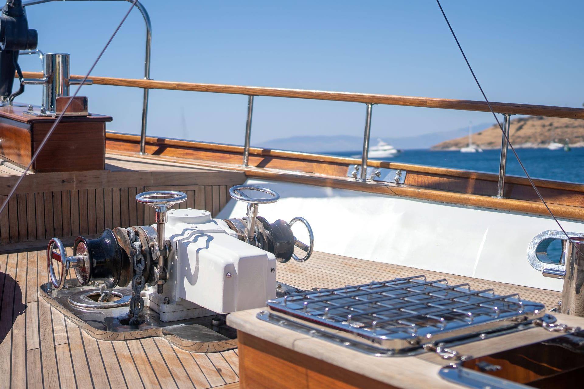 yacht deck showing white anchor windlass, stainless steel railings and teak decking