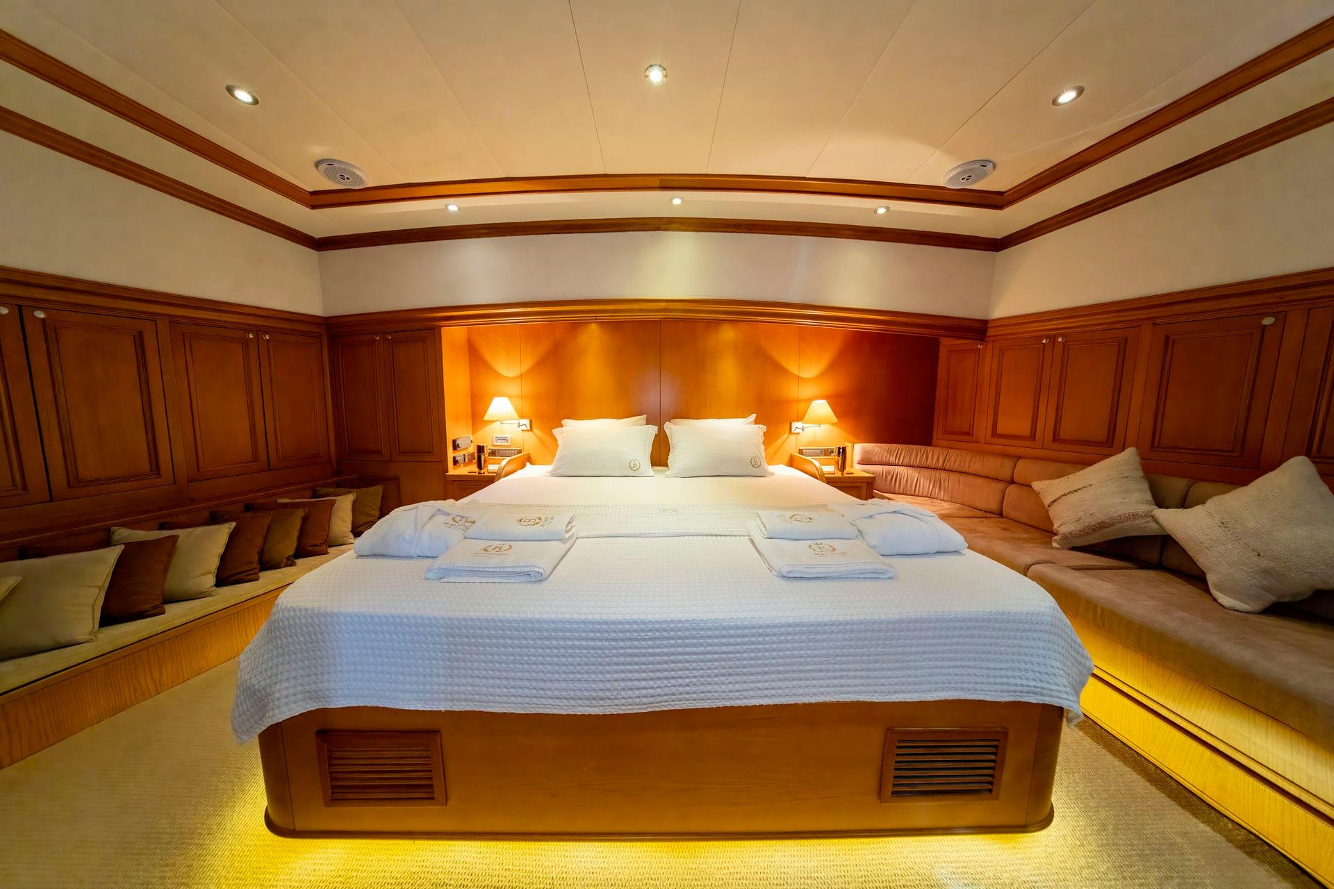 Master cabin with king bed, wood paneling, built-in seating and ambient lighting