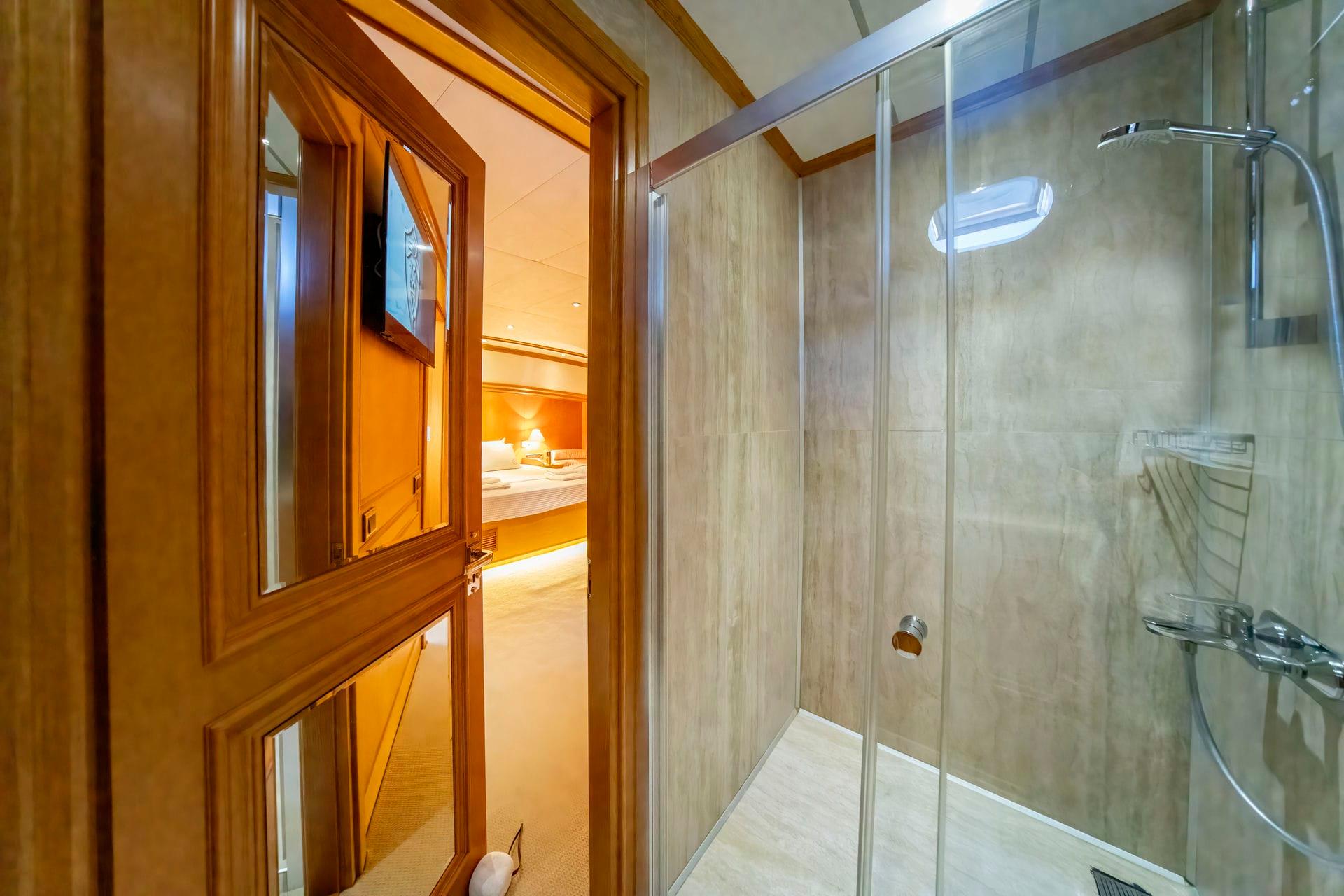 yacht bathroom with glass shower enclosure and view into cabin bedroom