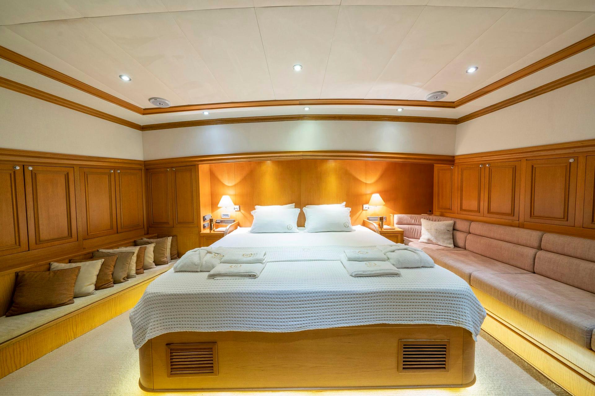 spacious yacht master cabin featuring king bed with white linens and wooden paneling