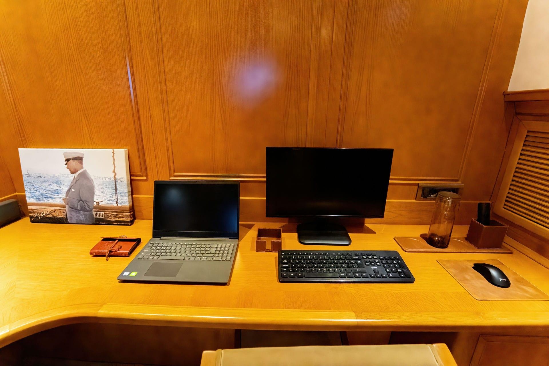 yacht office cabin with built-in wooden desk, laptop and desktop computer setup
