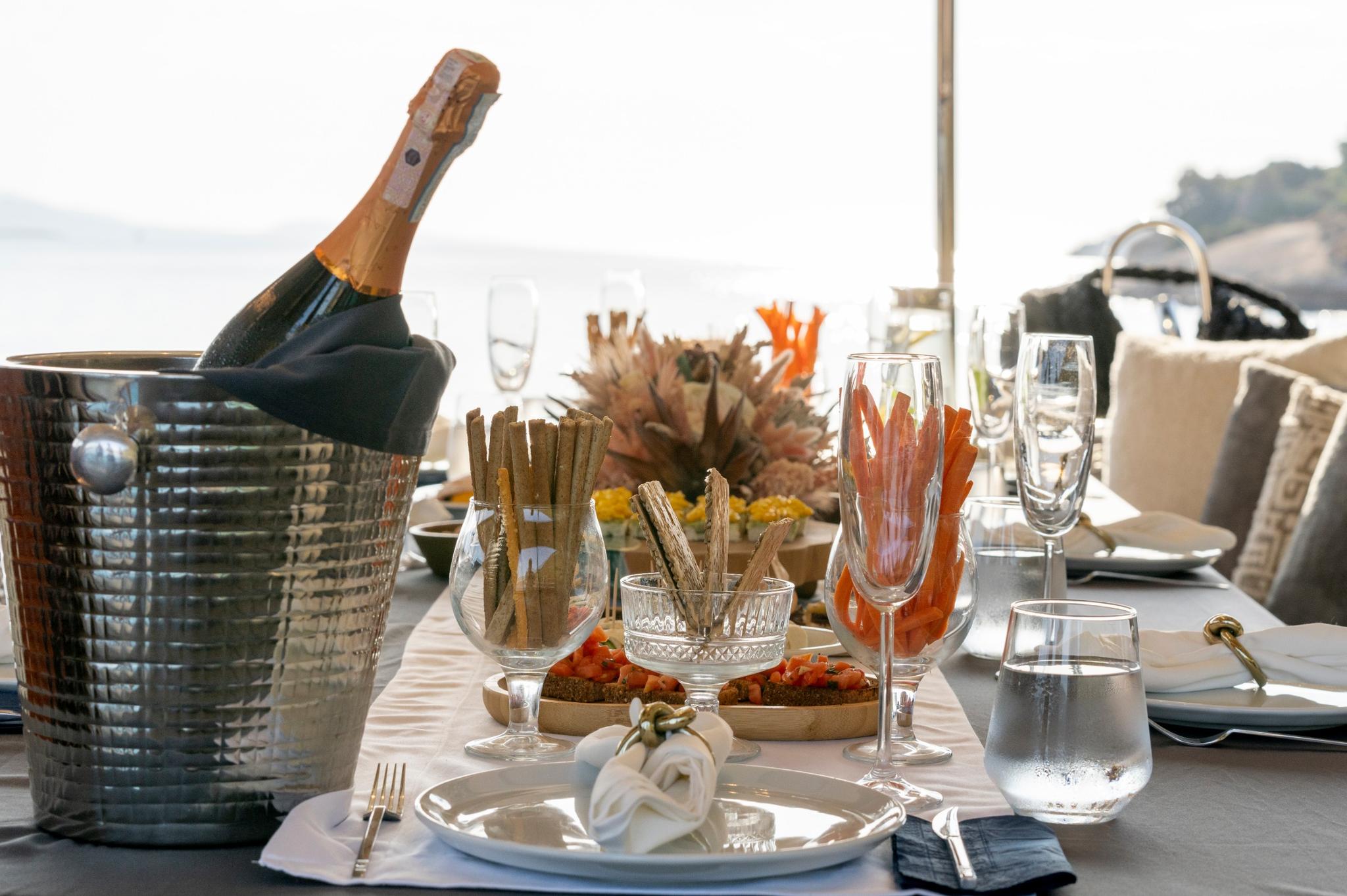 yacht dining table with champagne bottle, crystal glasses, appetizers and elegant table setting