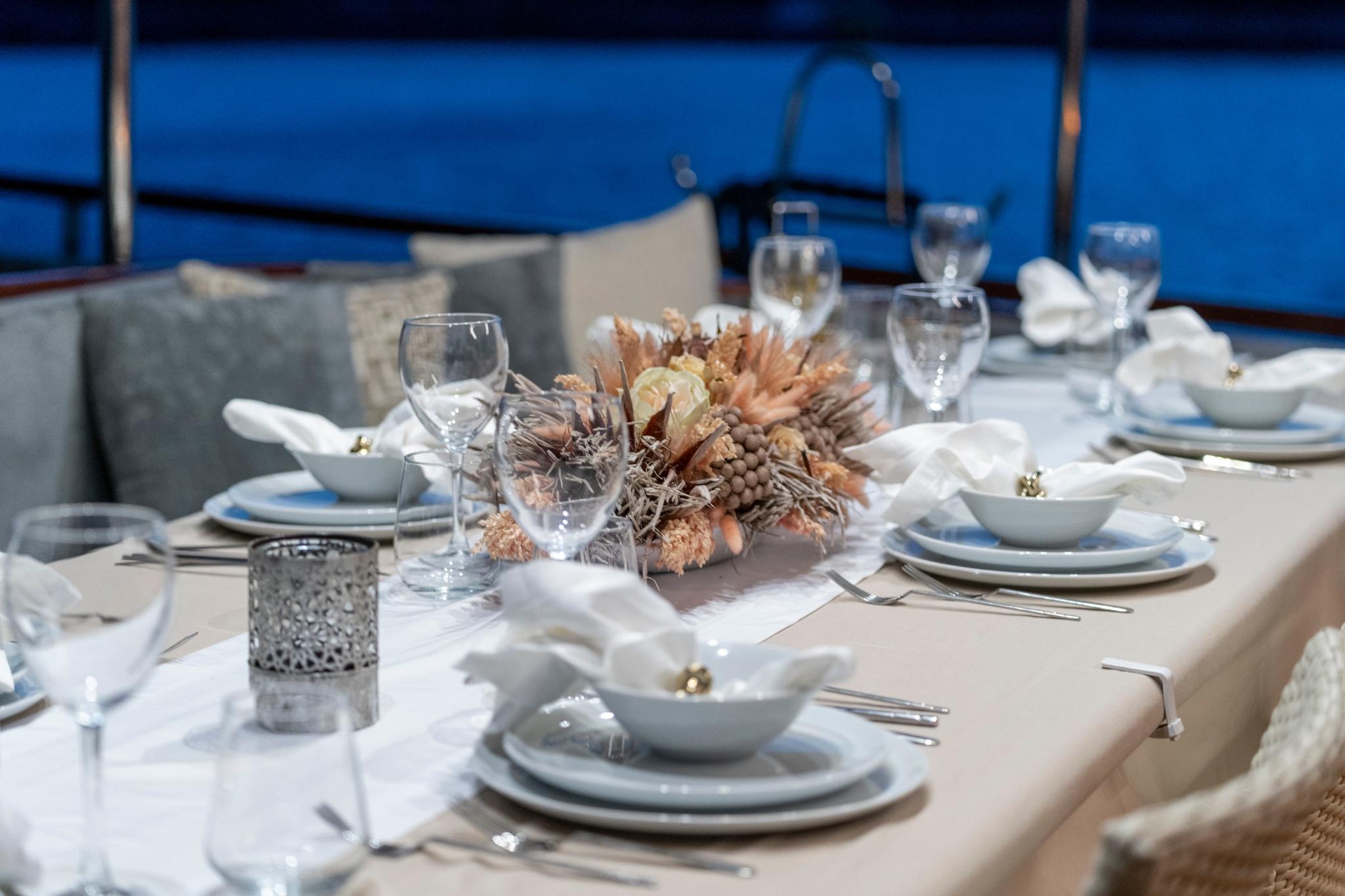 formal dining table setting with white plates, wine glasses and natural centerpiece arrangement