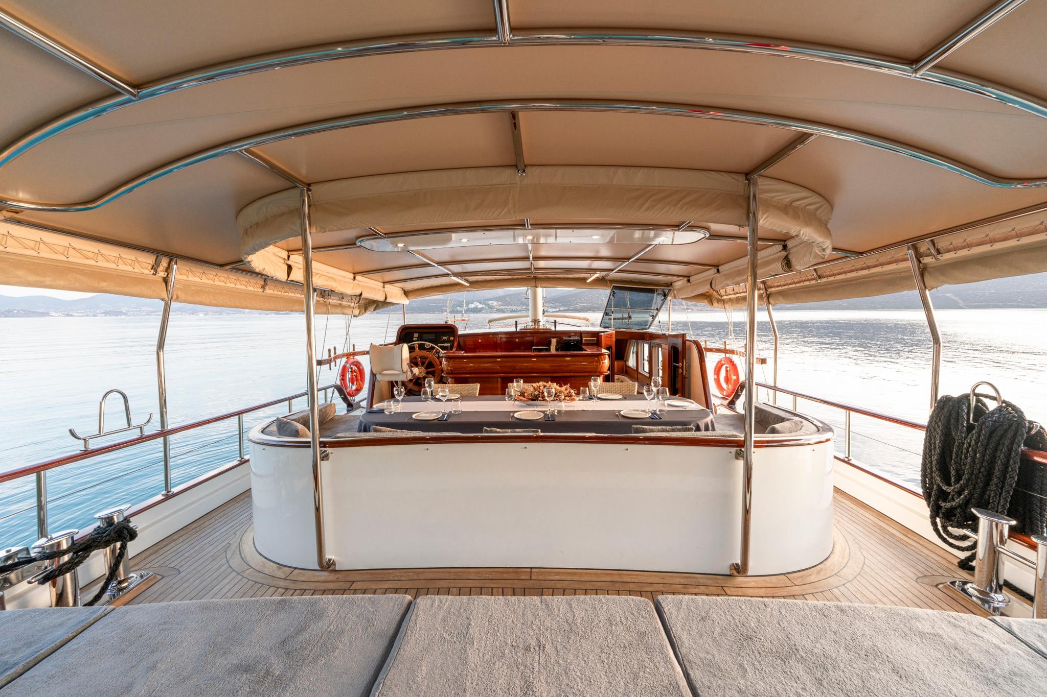 gulet aft deck with covered dining table and helm station under beige awning