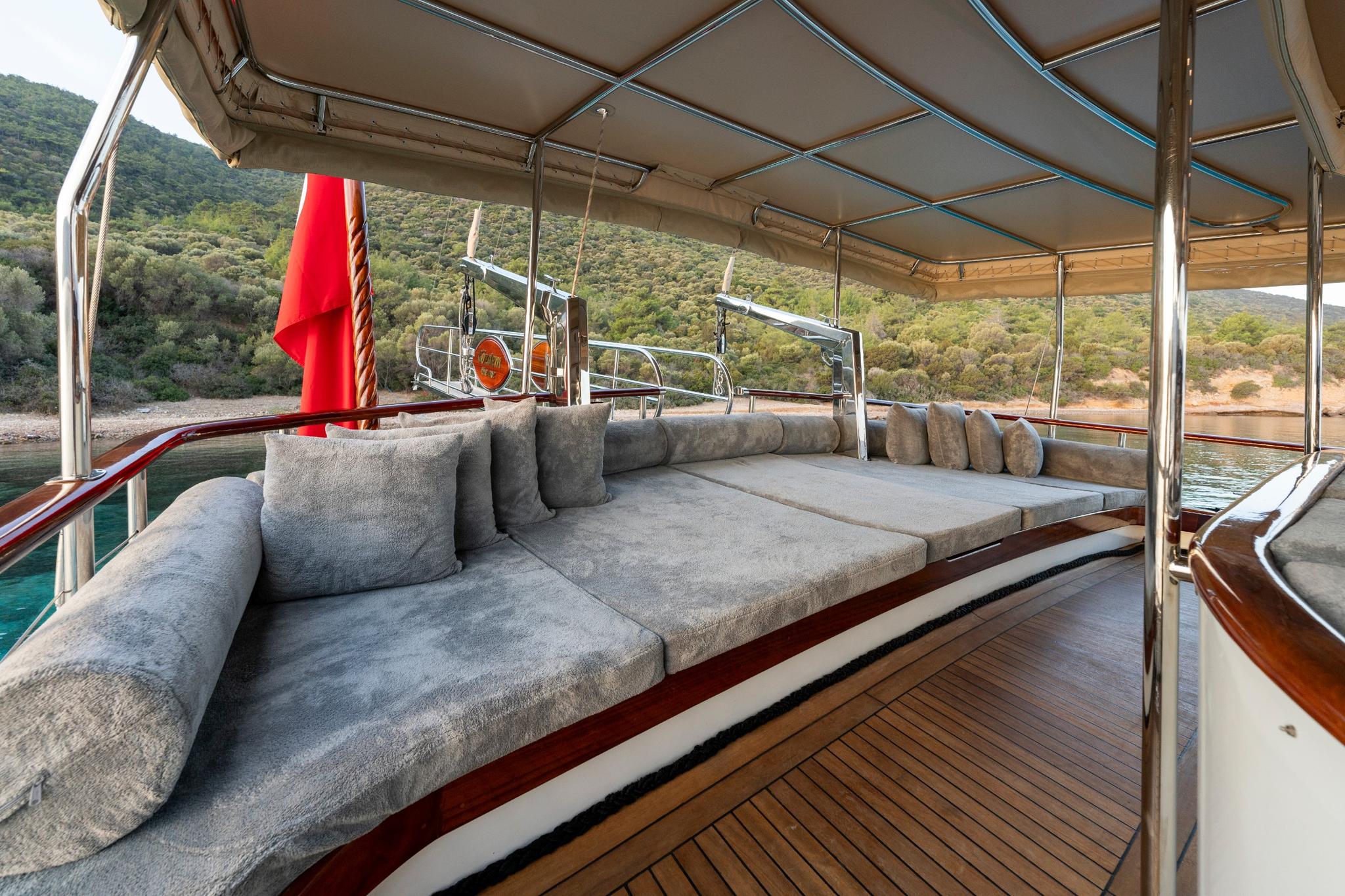 covered aft deck lounge area with grey sectional seating and teak decking