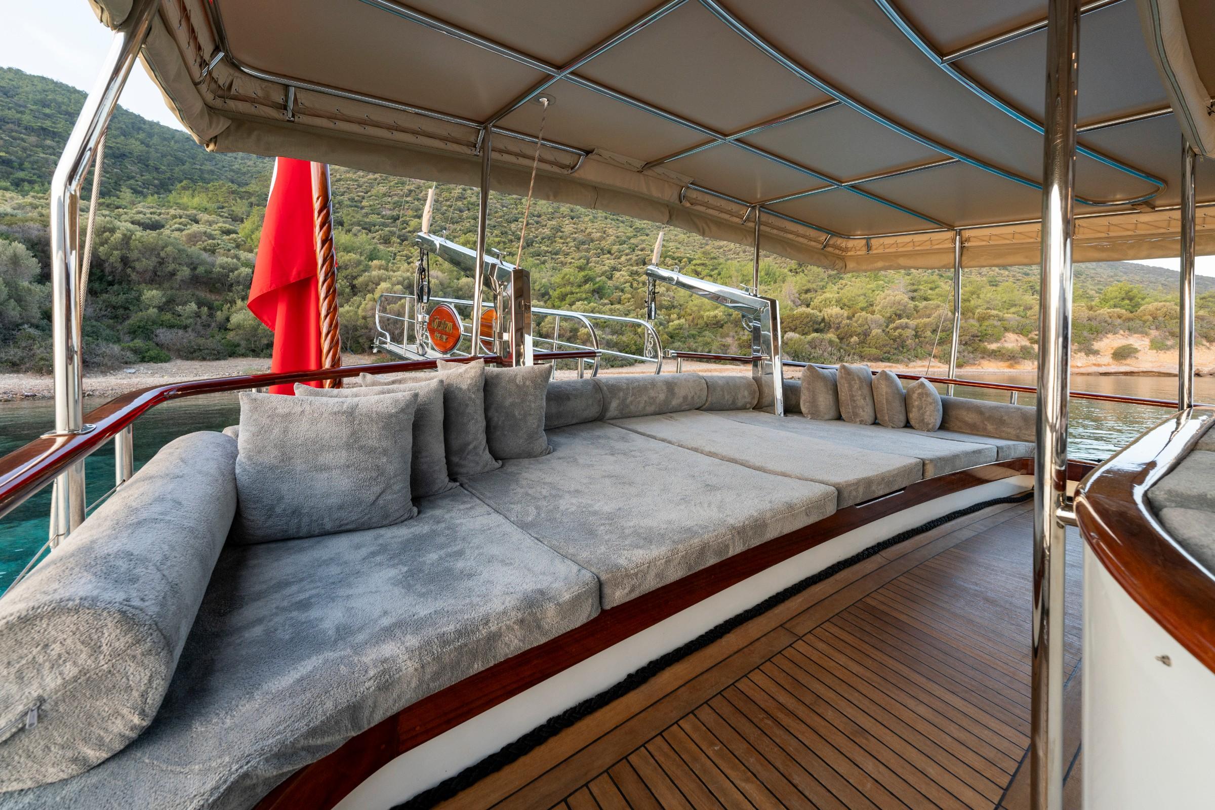covered aft deck lounge area with grey sectional seating and teak decking
