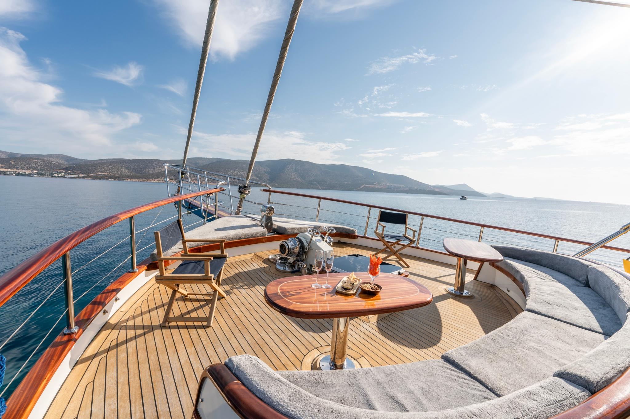 bow deck curved seating banquette with teak table and stainless steel windlass anchor system
