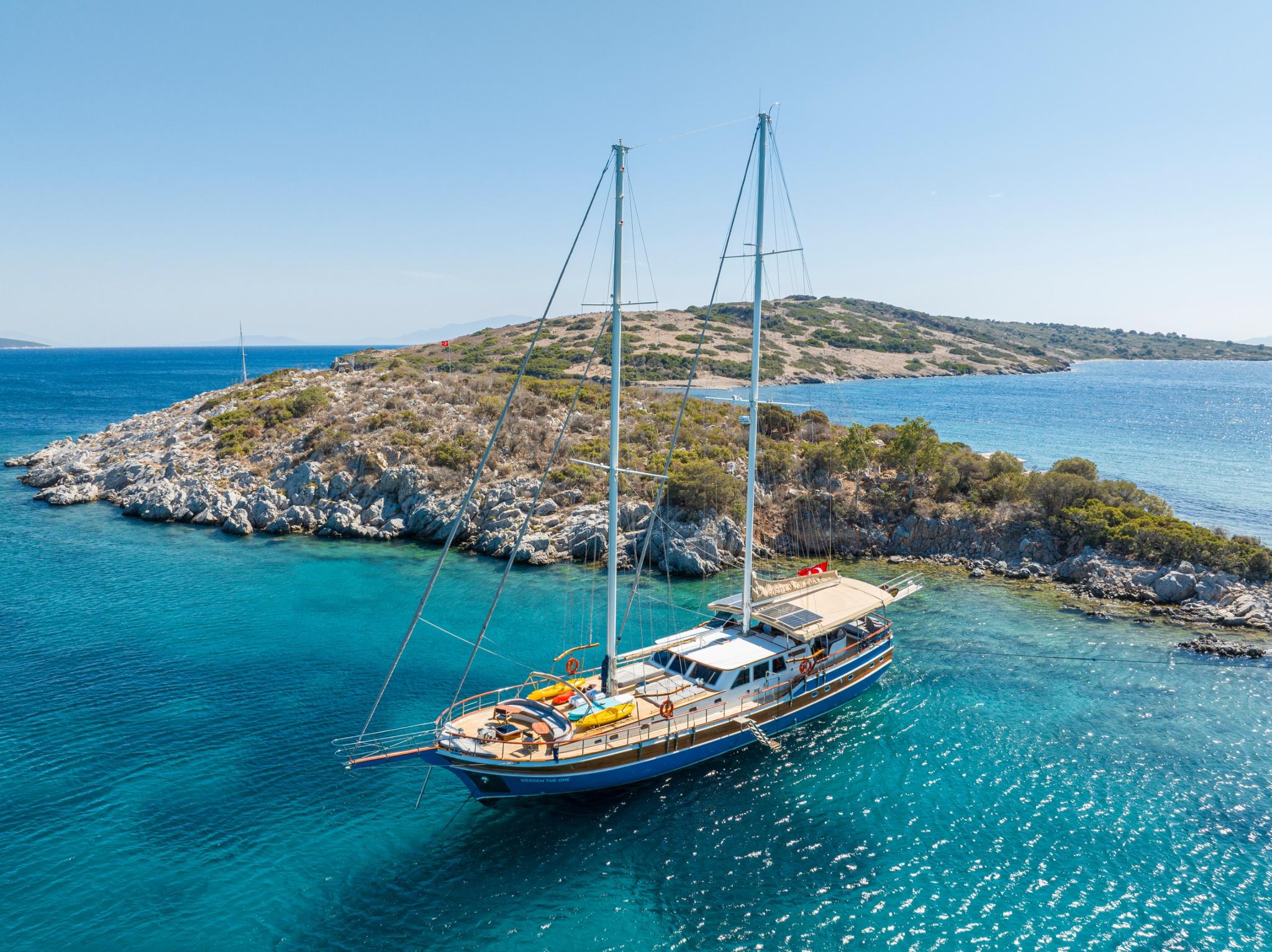 aerial view of traditional gulet yacht anchored in crystal clear turquoise waters near Mediterranean coastline