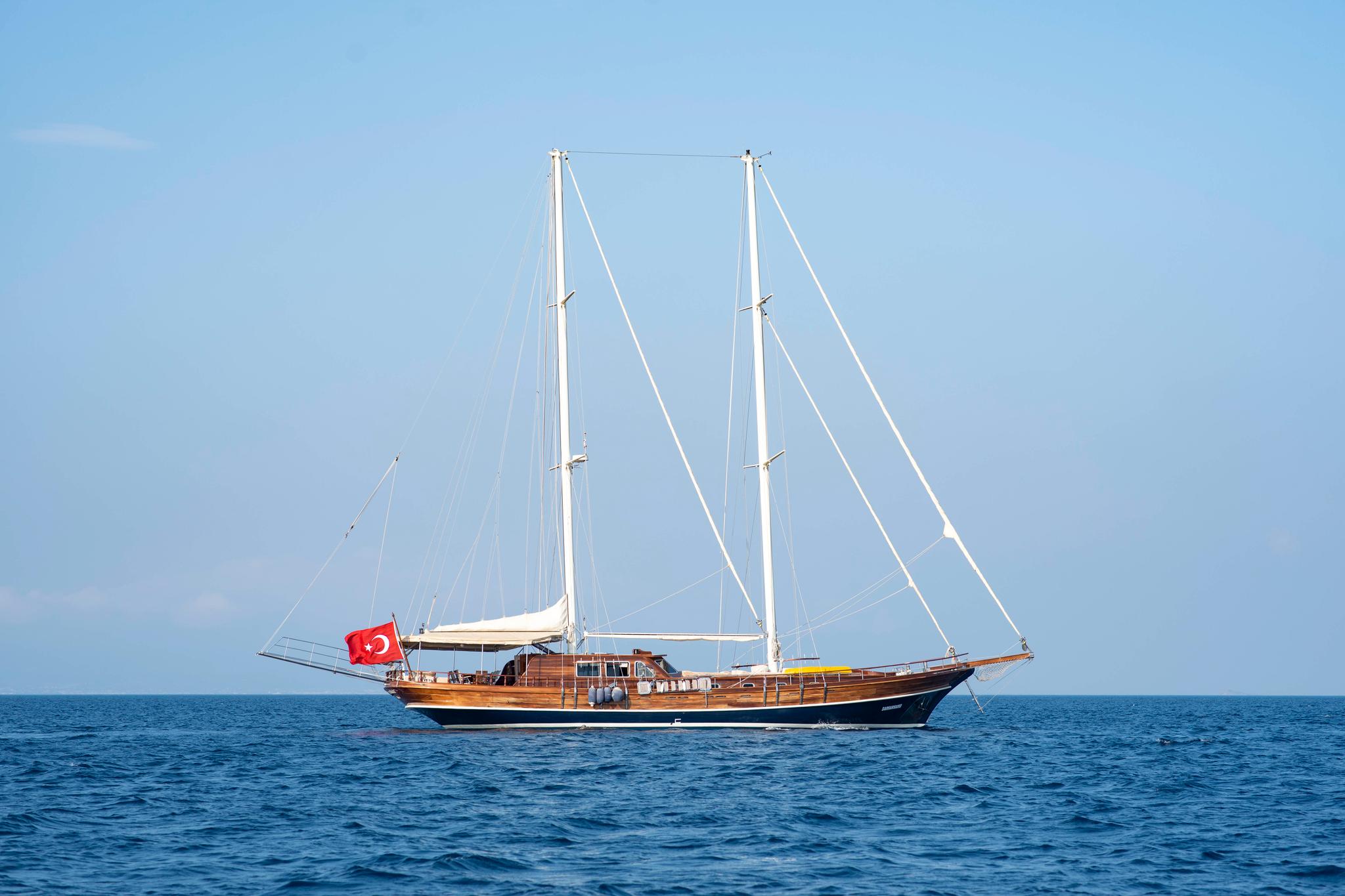 Traditional wooden gulet with two masts and Turkish flag sailing on calm blue Mediterranean waters