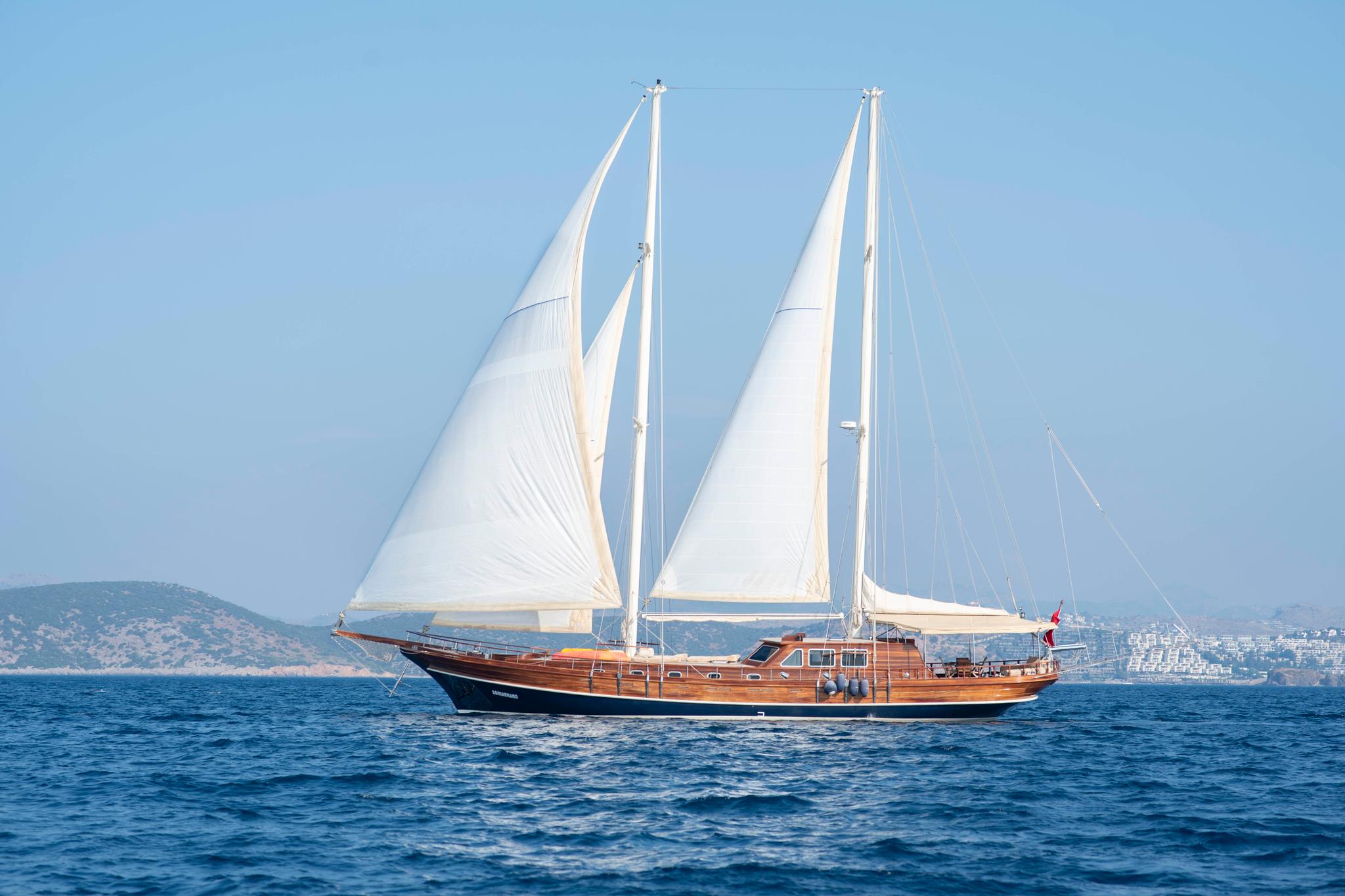 wooden gulet yacht with white sails raised sailing on calm blue Mediterranean waters