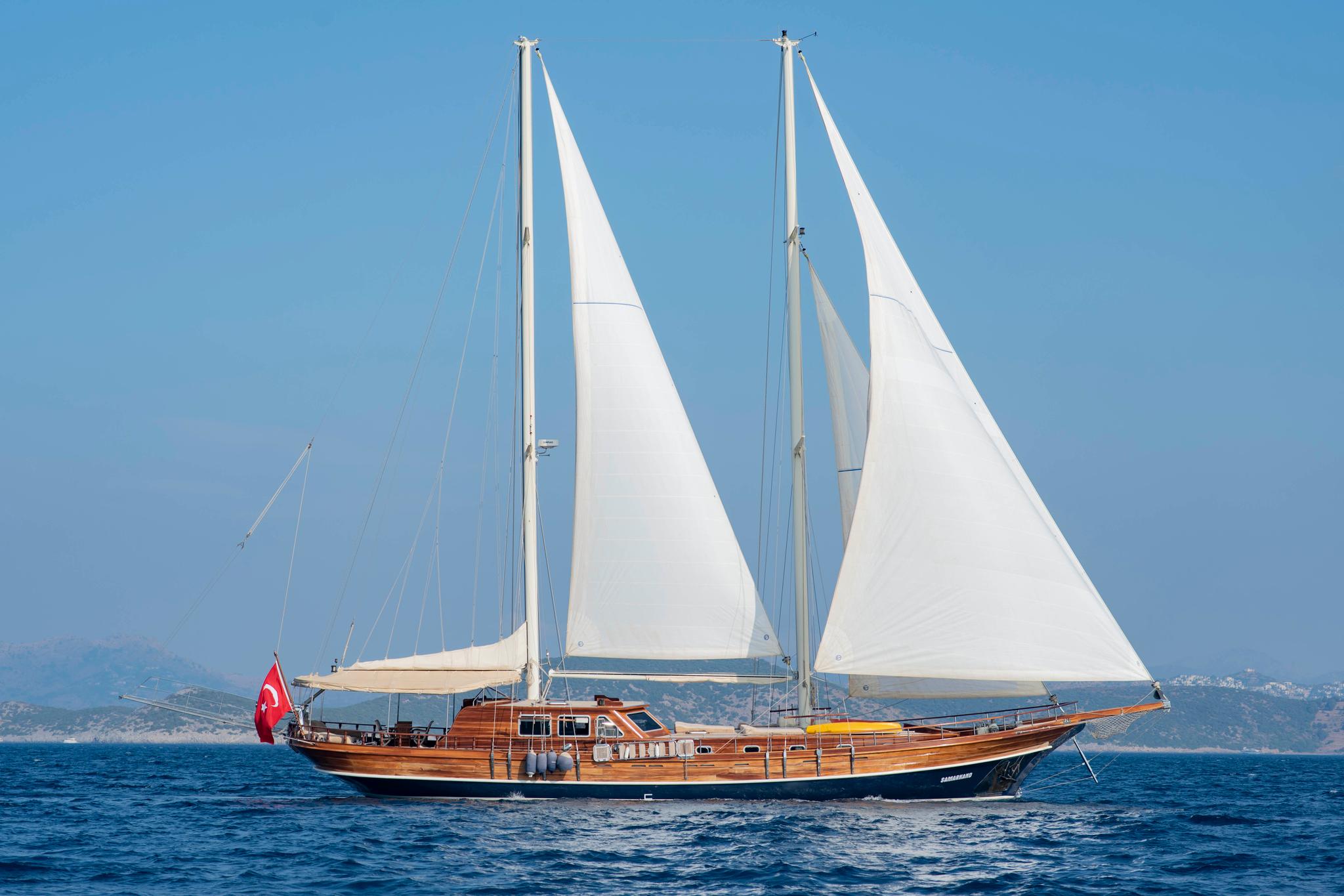 Traditional wooden gulet yacht sailing with white sails raised against blue Mediterranean waters