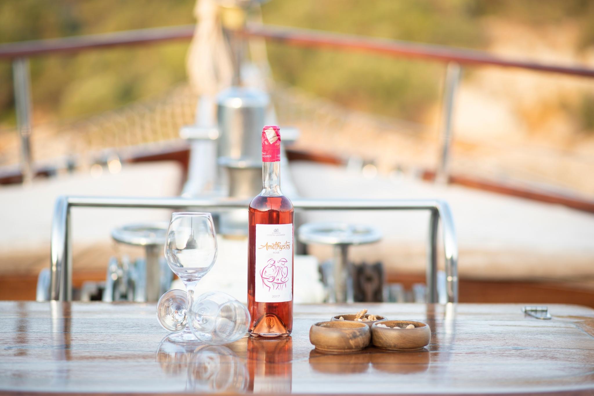rosé wine bottle with glasses and wooden bowls on yacht dining table