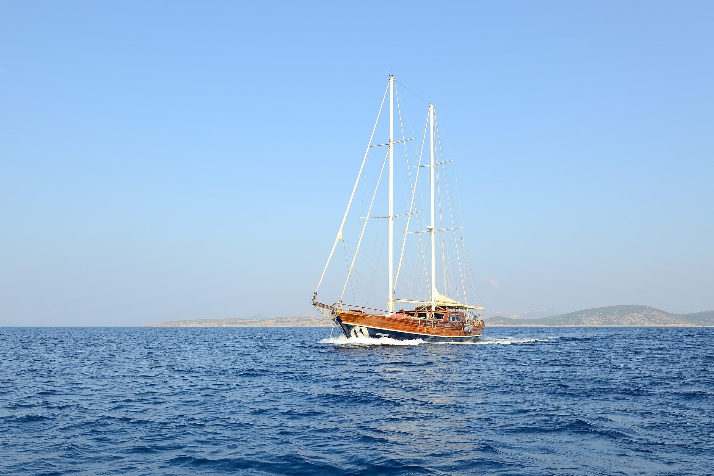 wooden gulet yacht under sail on Mediterranean waters with coastline in background