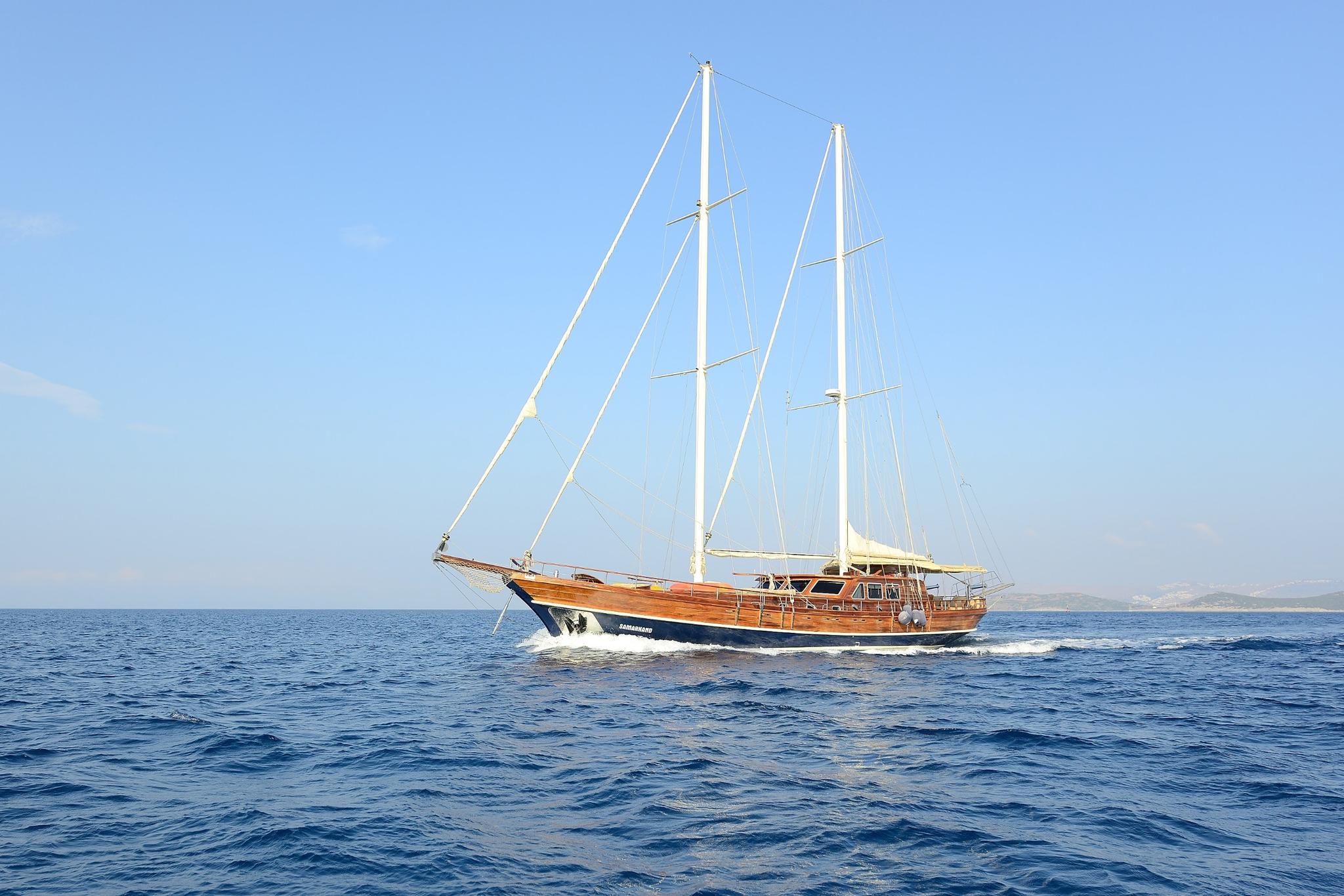 wooden gulet with two masts and rigging sailing through blue Mediterranean waters