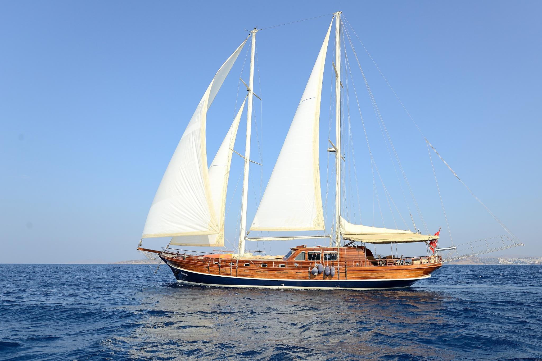 traditional wooden gulet yacht with white sails deployed sailing on calm blue Mediterranean waters