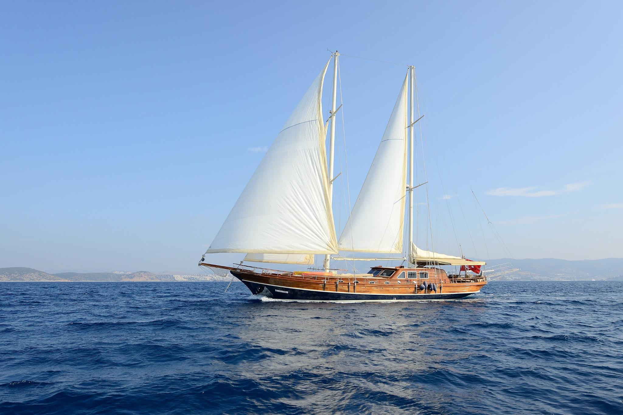 traditional wooden gulet sailing with white sails raised on deep blue Mediterranean waters