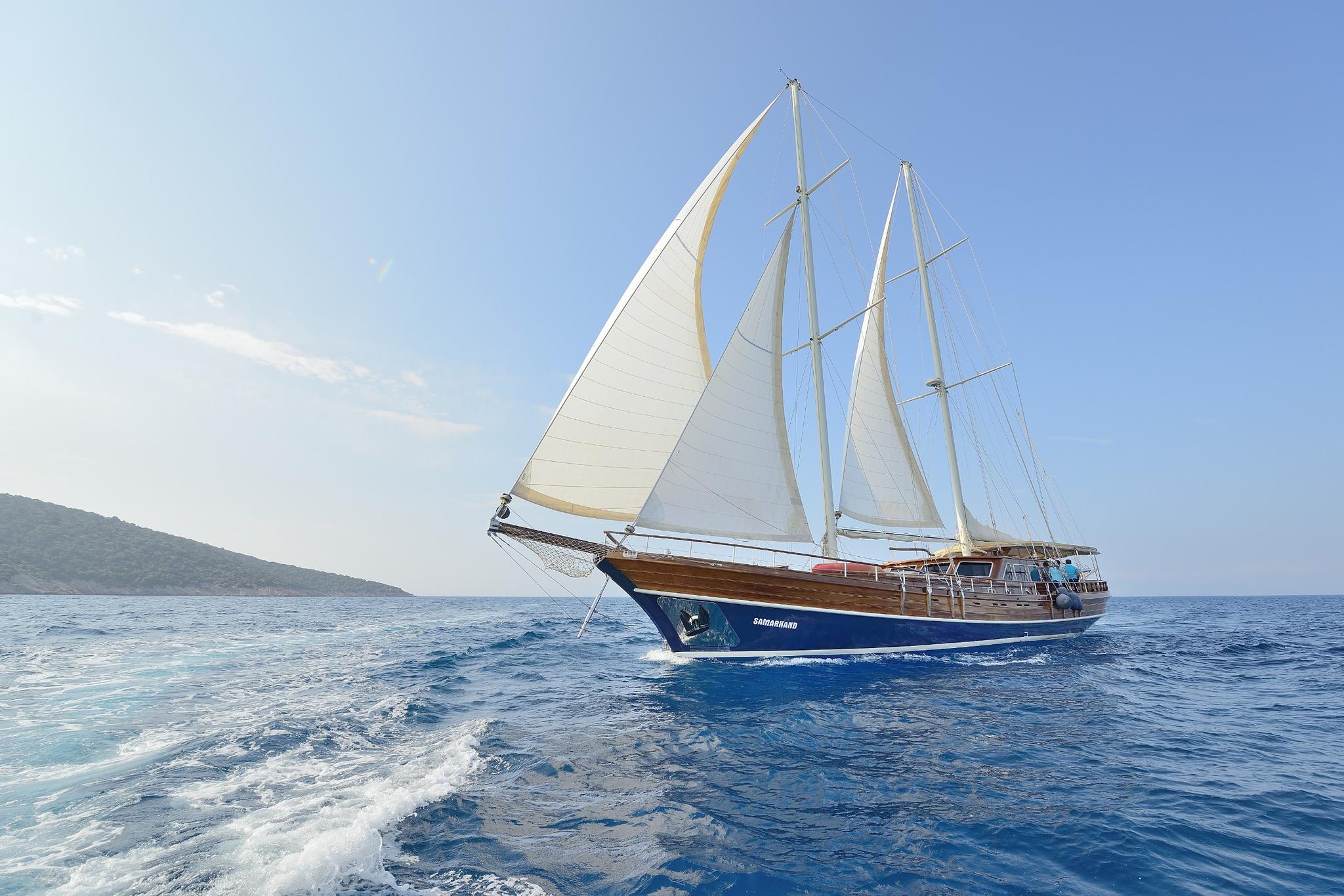 Traditional wooden gulet with white sails sailing on deep blue Mediterranean waters