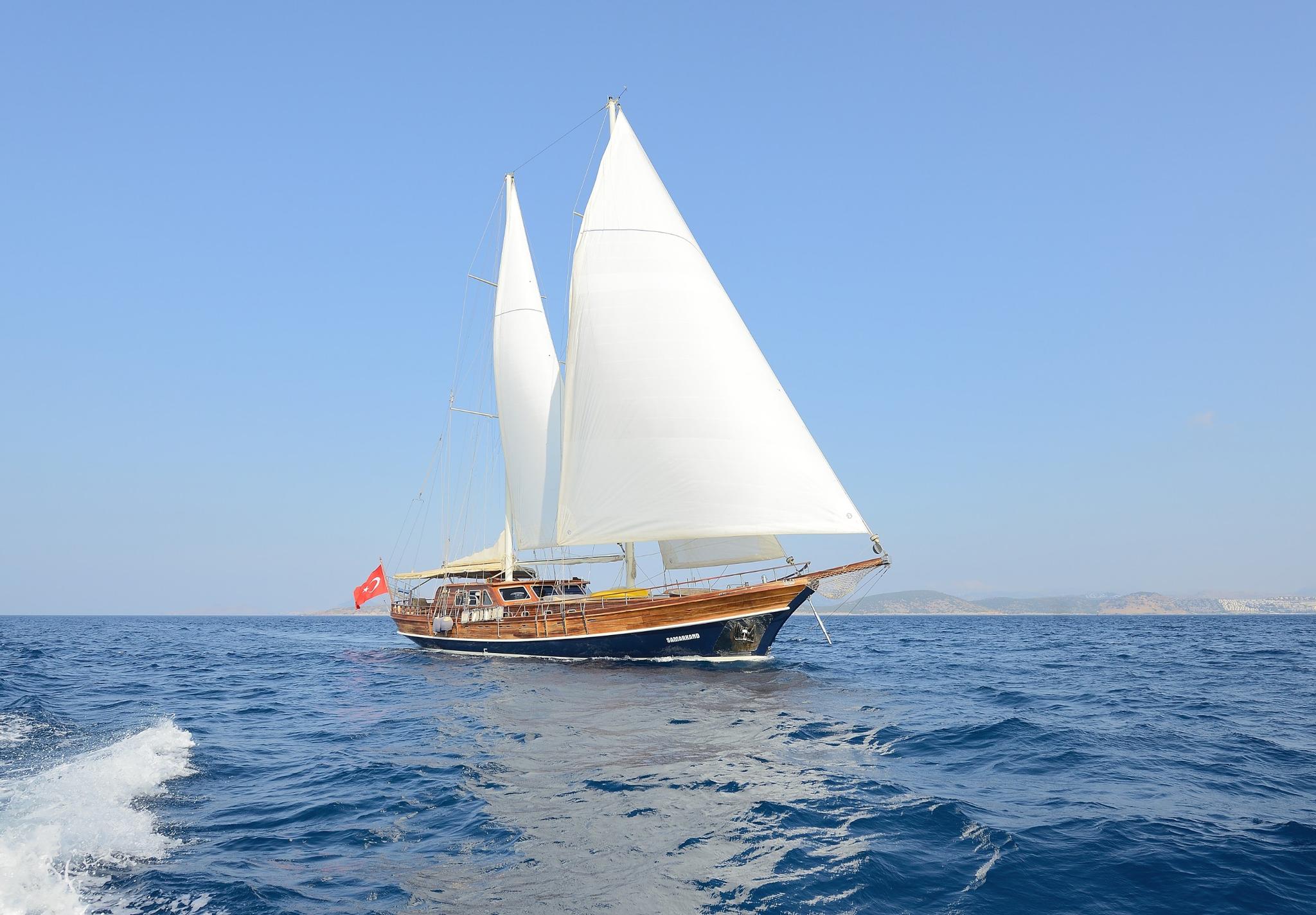 Traditional wooden gulet sailing with white sails raised on calm blue Mediterranean waters