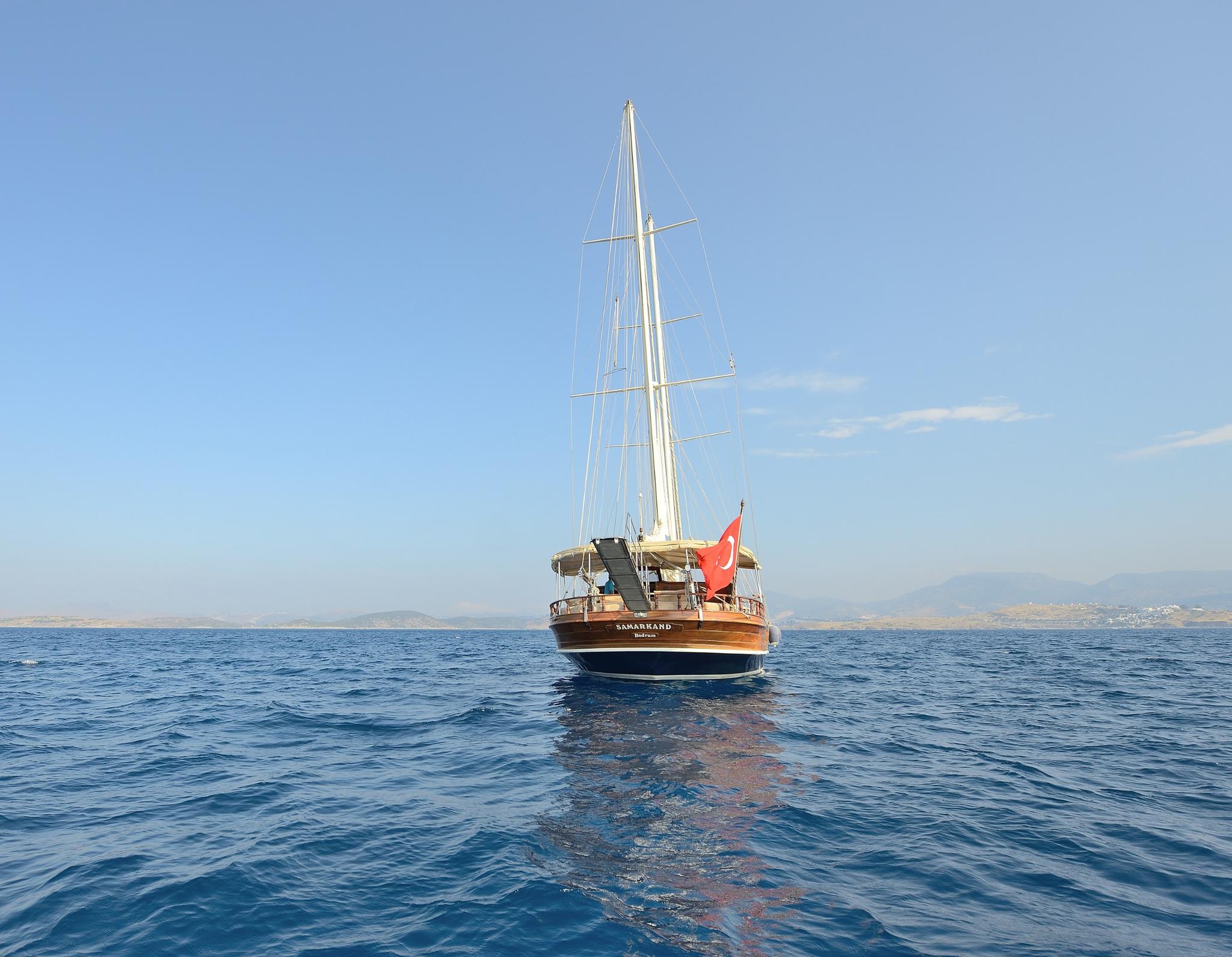 wooden gulet yacht with tall mast anchored in blue Mediterranean waters
