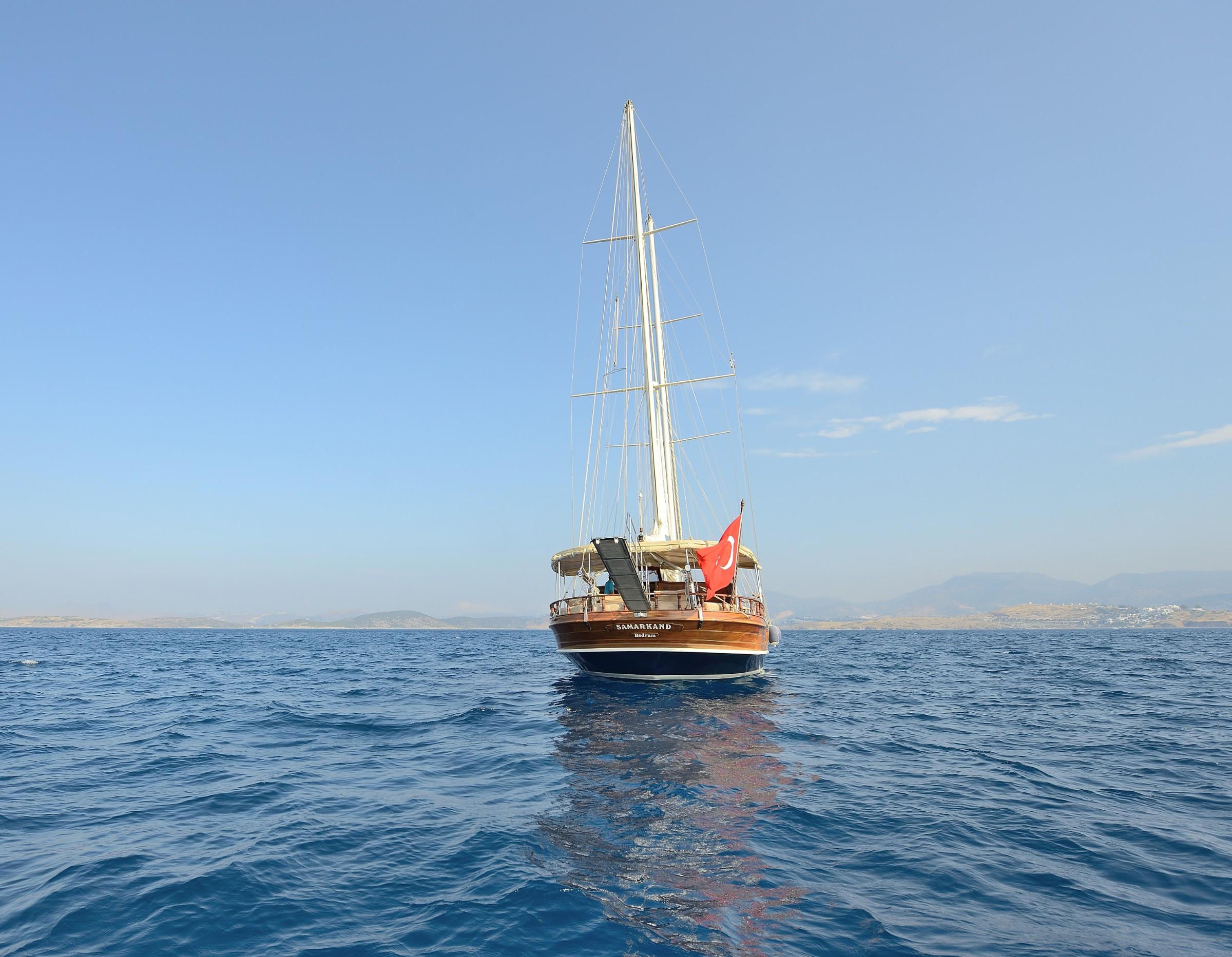 wooden gulet yacht with tall mast anchored in blue Mediterranean waters