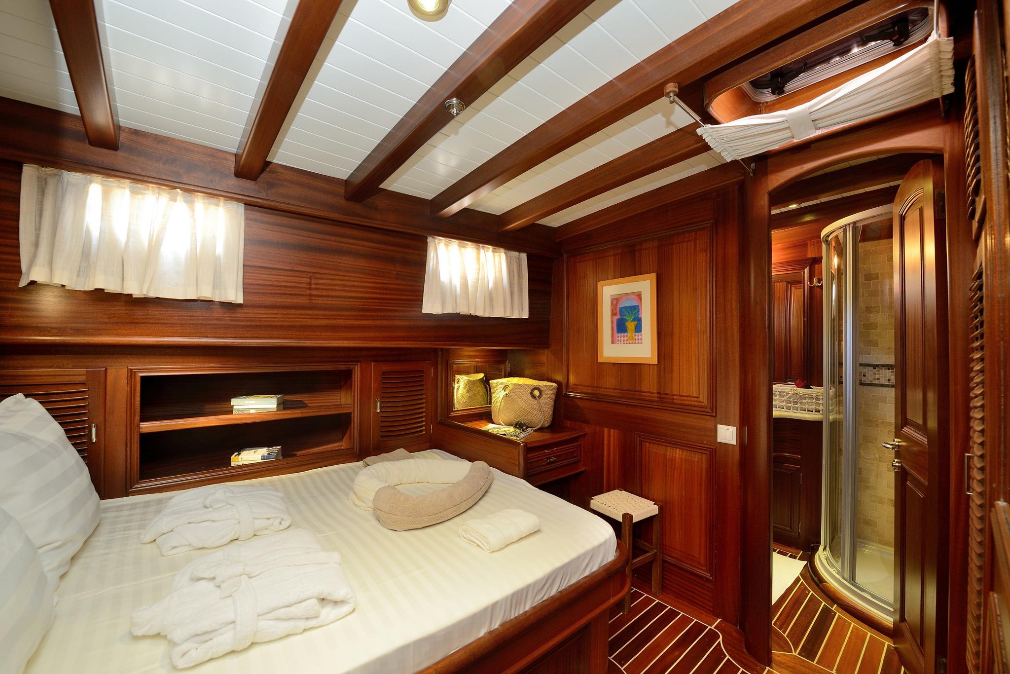 yacht guest cabin featuring double bed, built-in storage, portholes and en-suite shower room