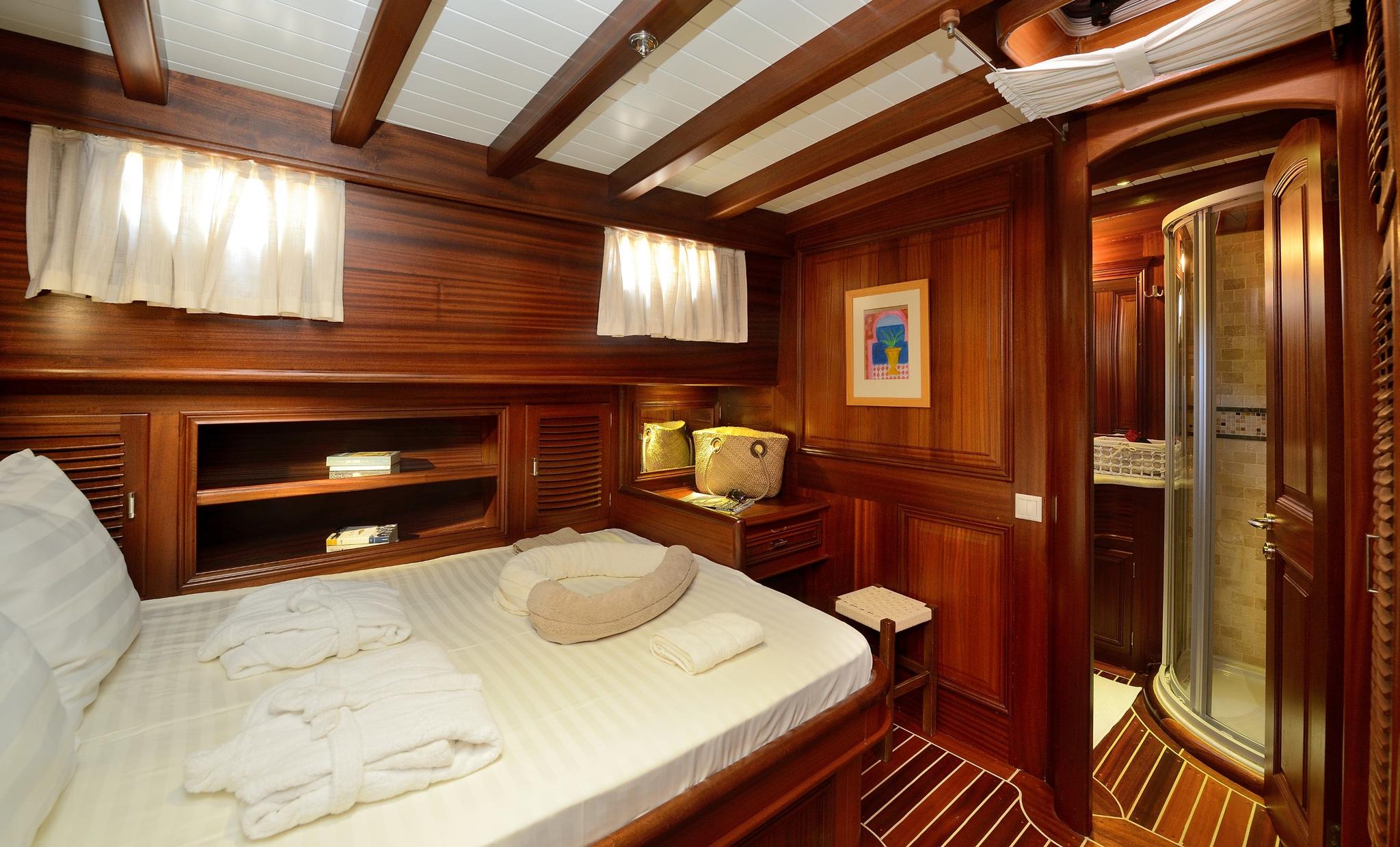 yacht guest cabin featuring double bed, built-in storage shelves, and en-suite bathroom entrance