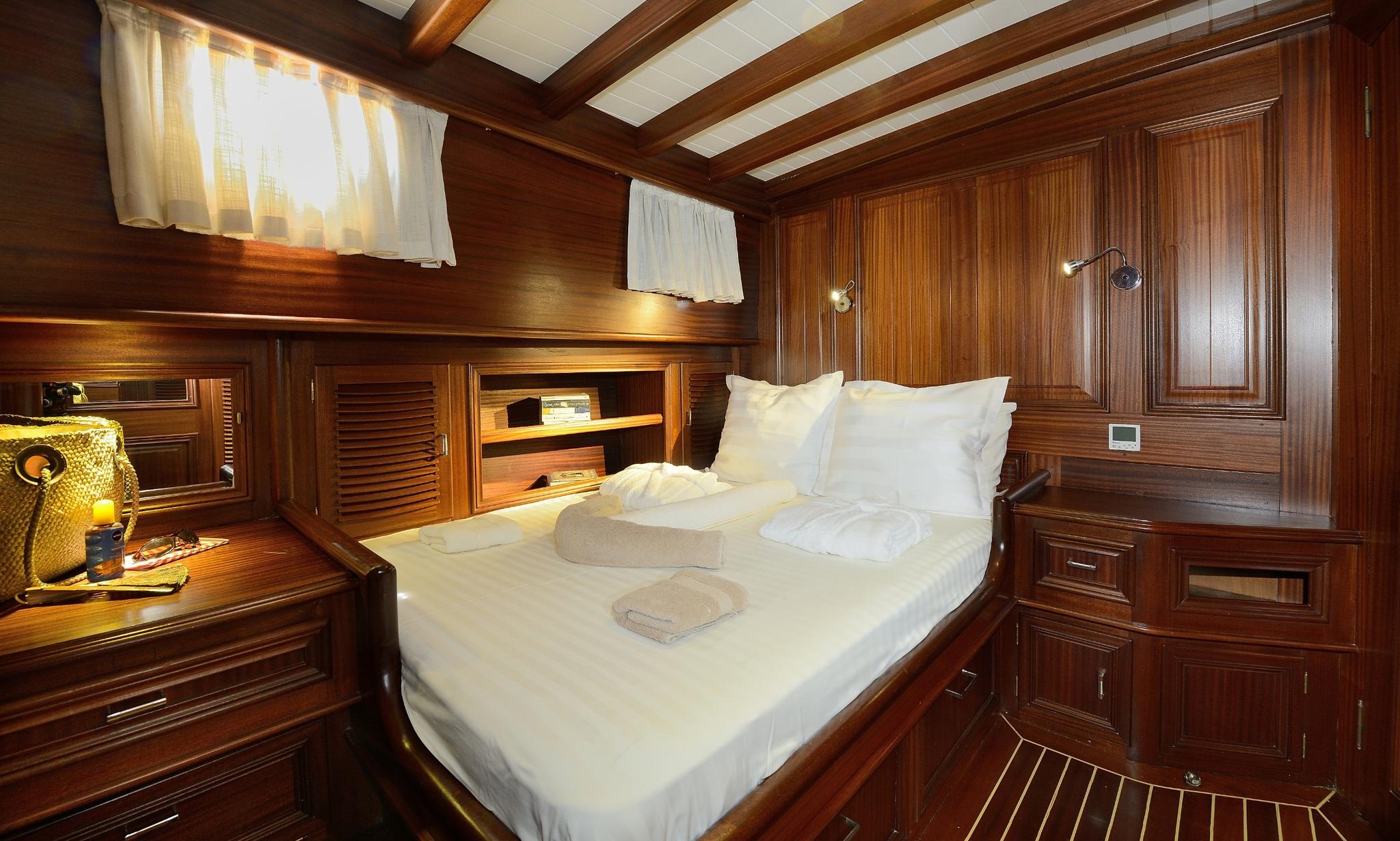 yacht guest cabin with double bed, rich wood paneling, and built-in storage