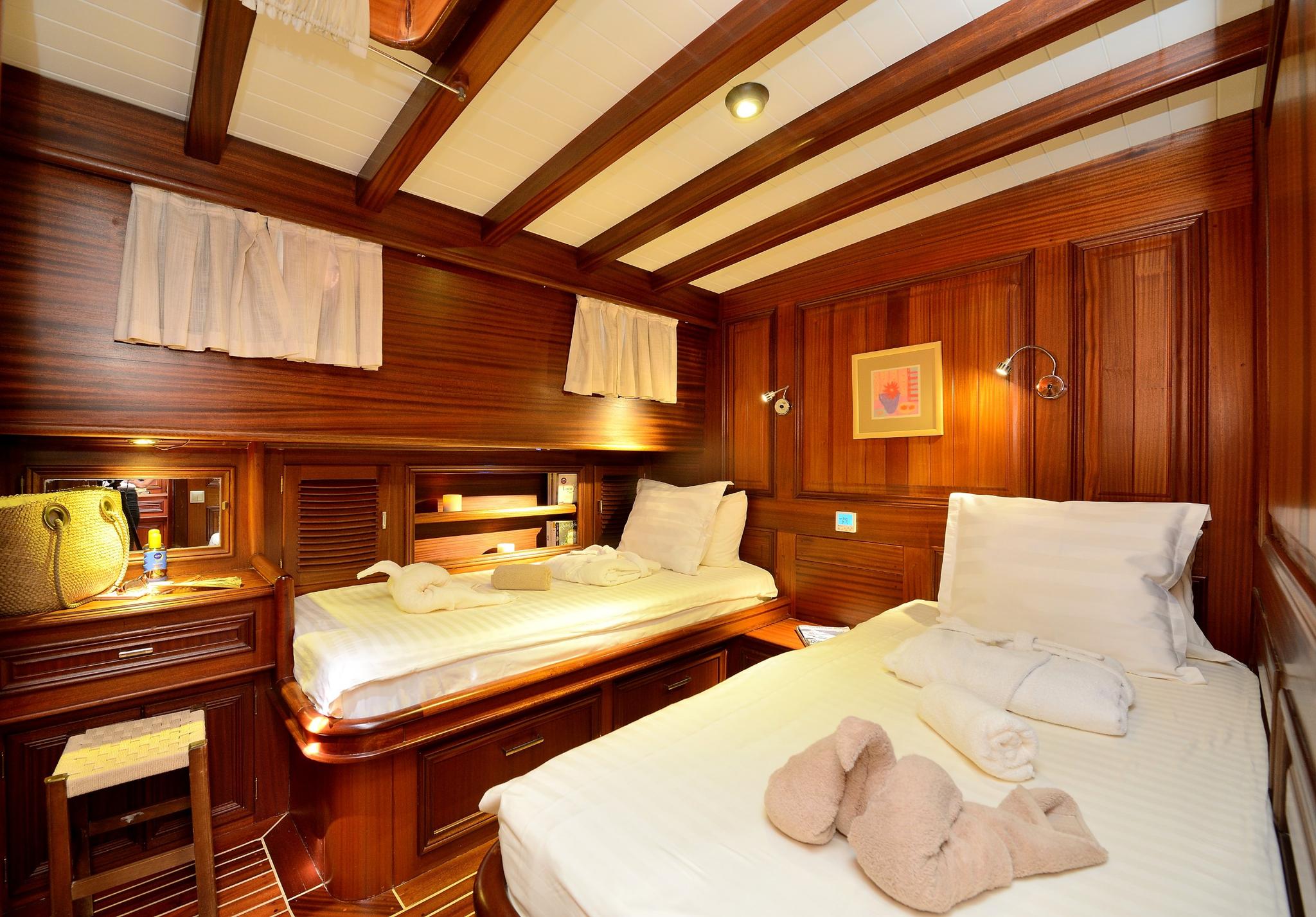 yacht twin cabin featuring two single beds with white linens and rich wood paneling