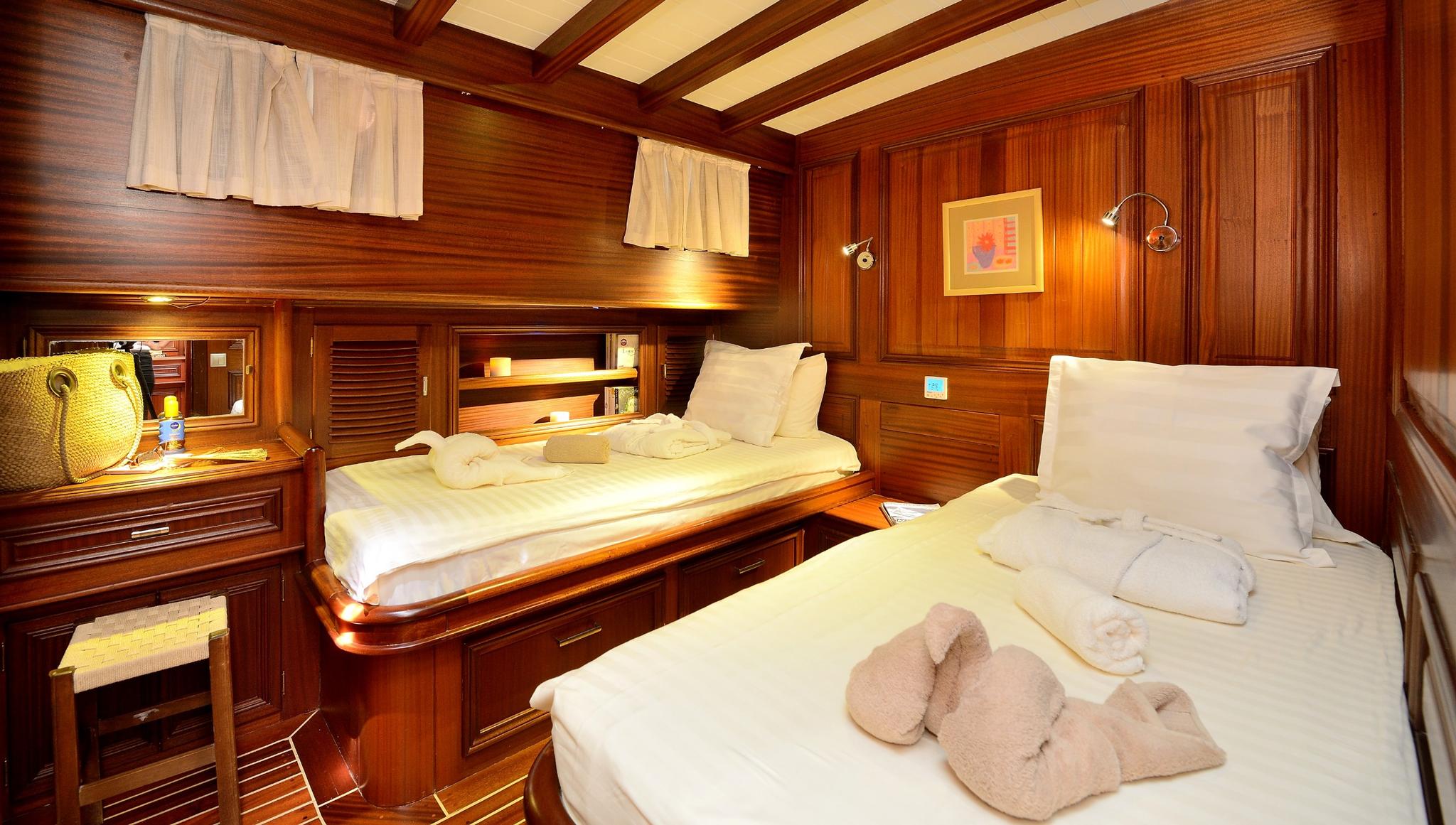yacht twin cabin with two single beds, rich teak paneling and built-in storage