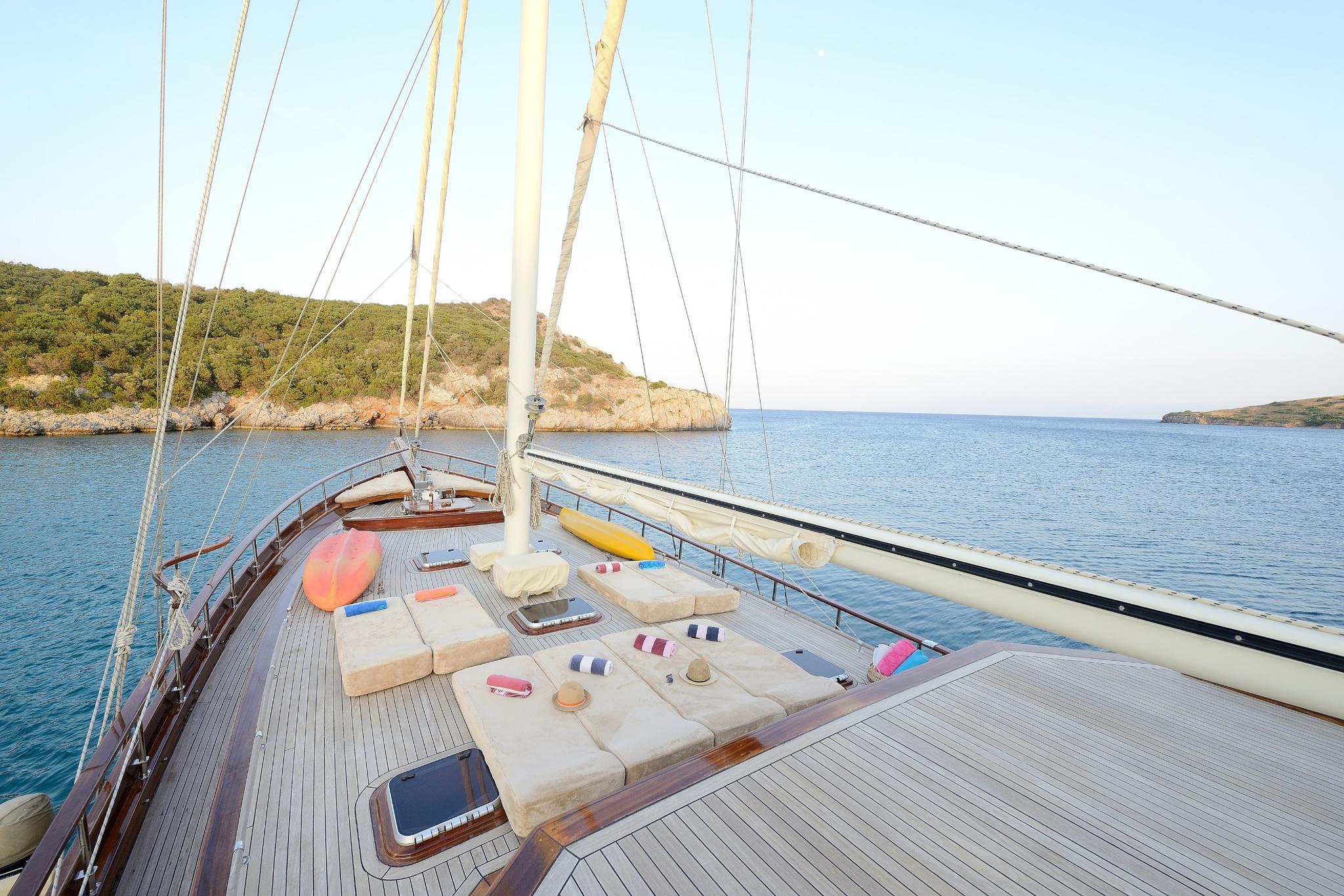 gulet bow deck with cream sunbathing cushions and pillows arranged on teak decking