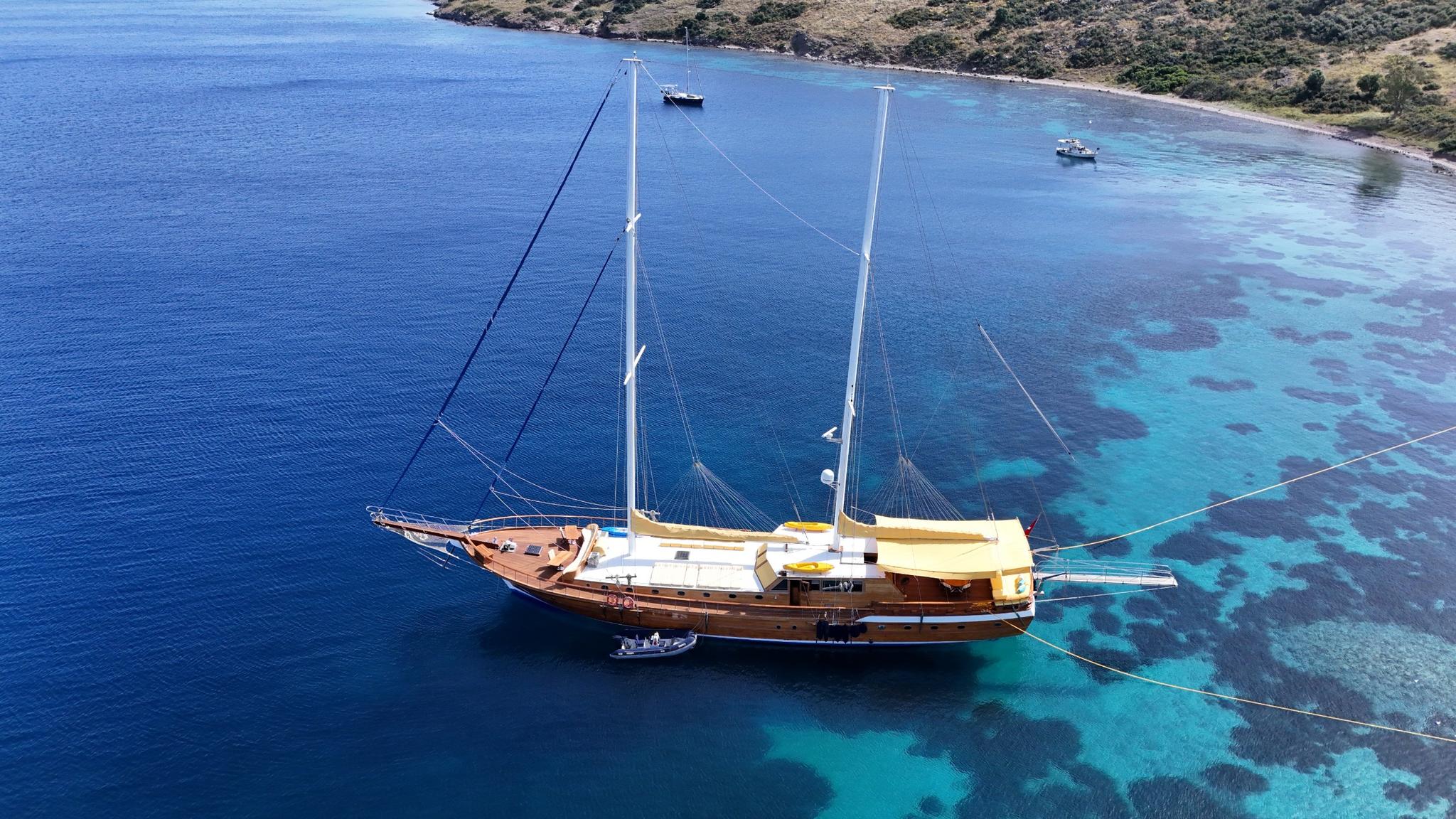 aerial view of traditional wooden gulet yacht anchored in crystal clear turquoise Mediterranean bay