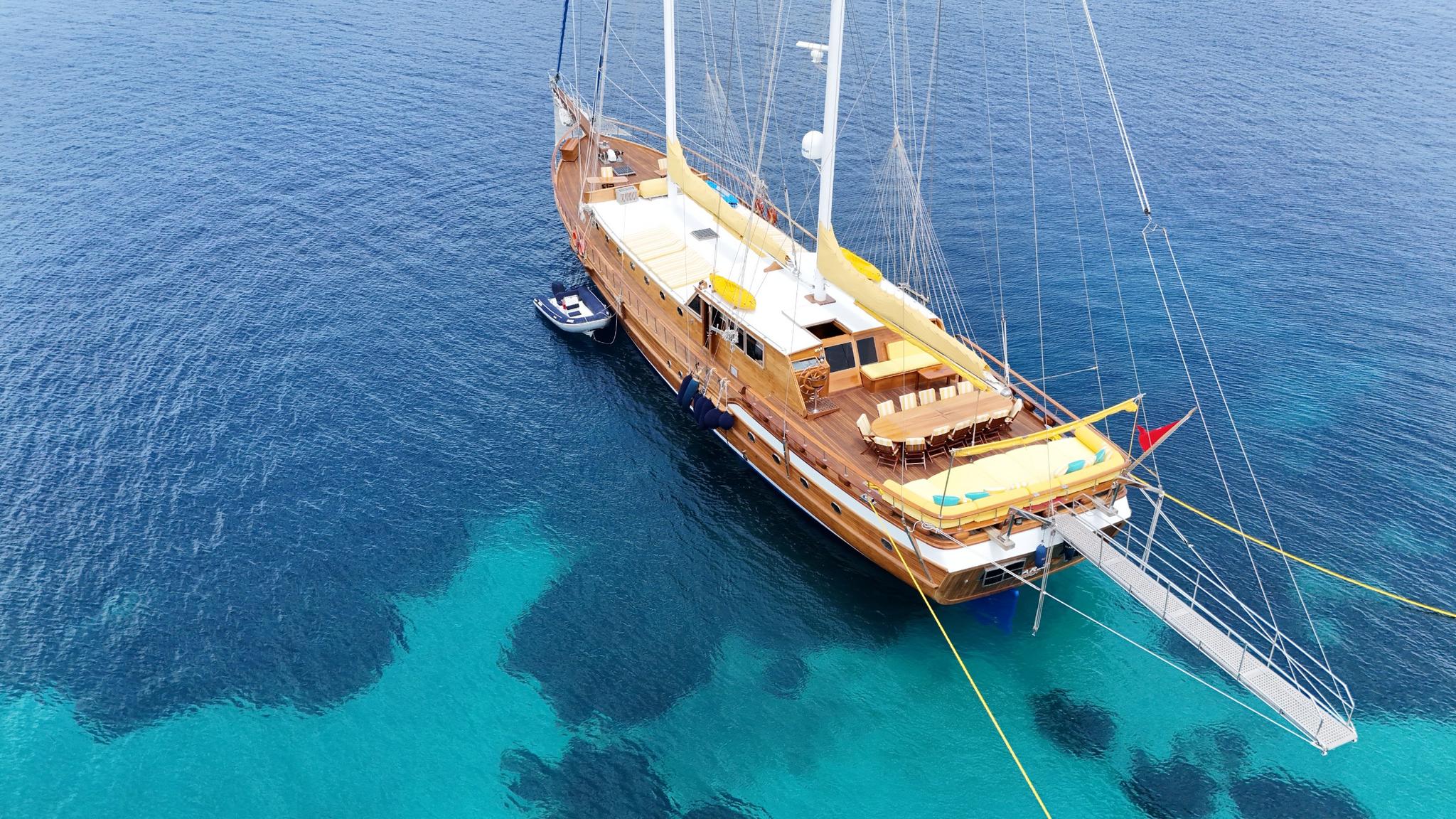 aerial view of traditional wooden gulet yacht anchored in crystal clear turquoise Mediterranean waters