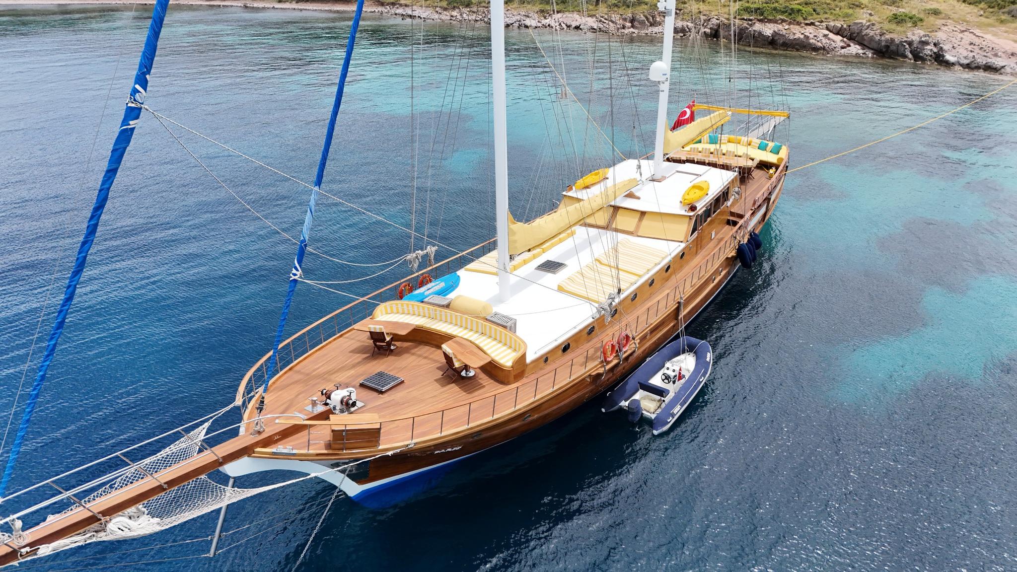 aerial drone shot of traditional wooden gulet yacht anchored in crystal clear turquoise Mediterranean bay