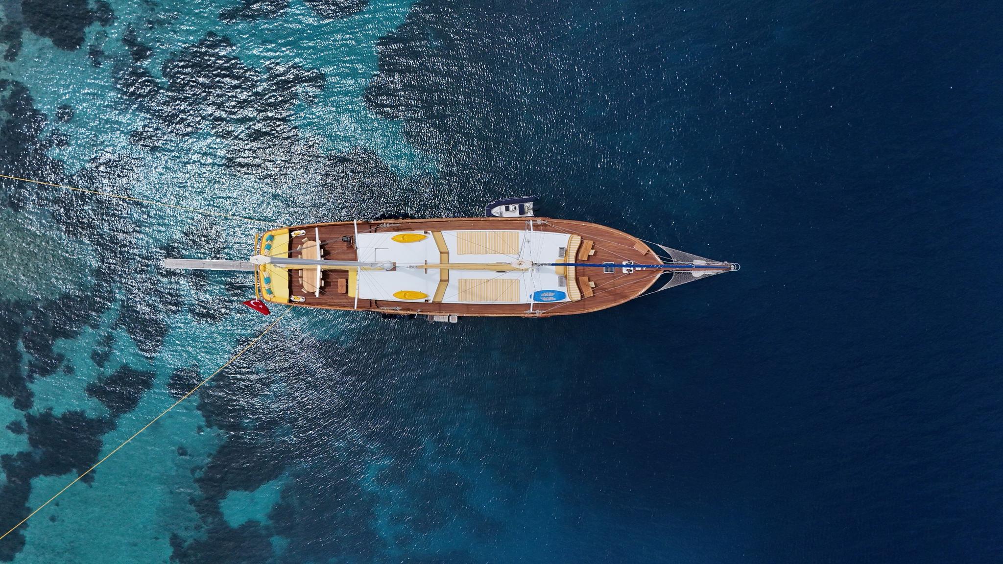 aerial view of traditional wooden gulet yacht anchored in crystal clear turquoise waters