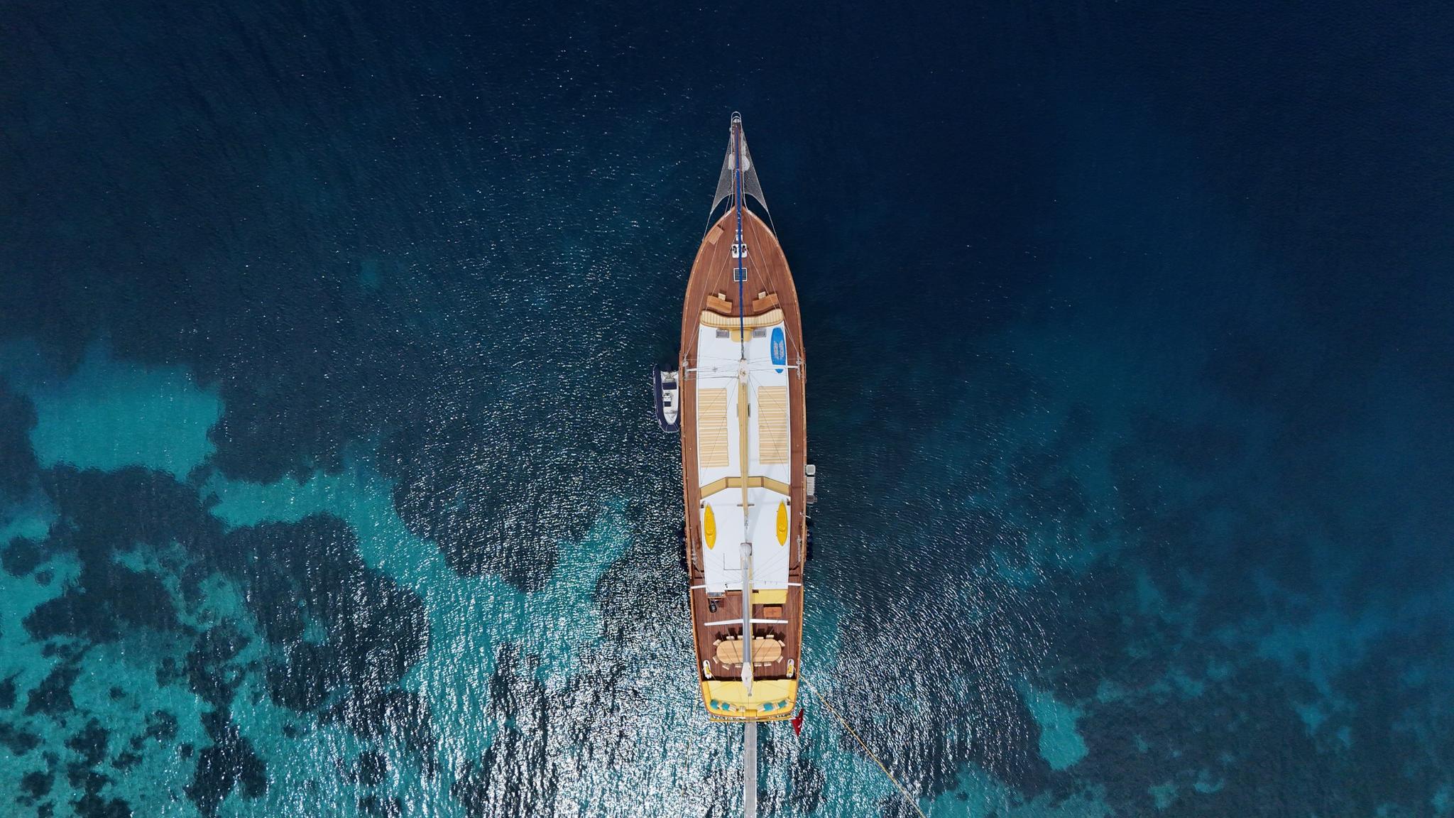 aerial drone shot of traditional gulet yacht anchored in crystal clear turquoise Mediterranean waters