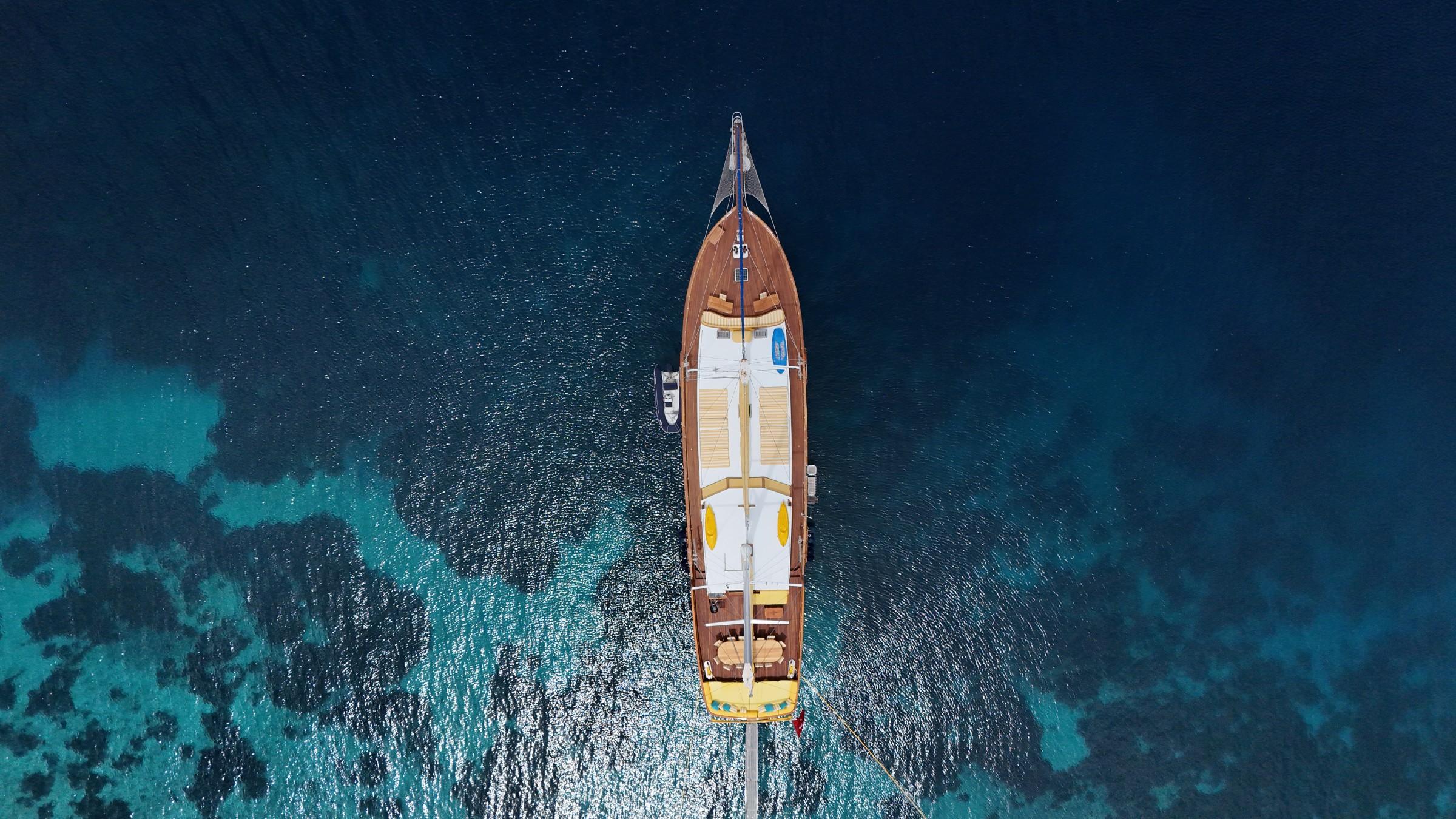 aerial drone shot of traditional gulet yacht anchored in crystal clear turquoise Mediterranean waters