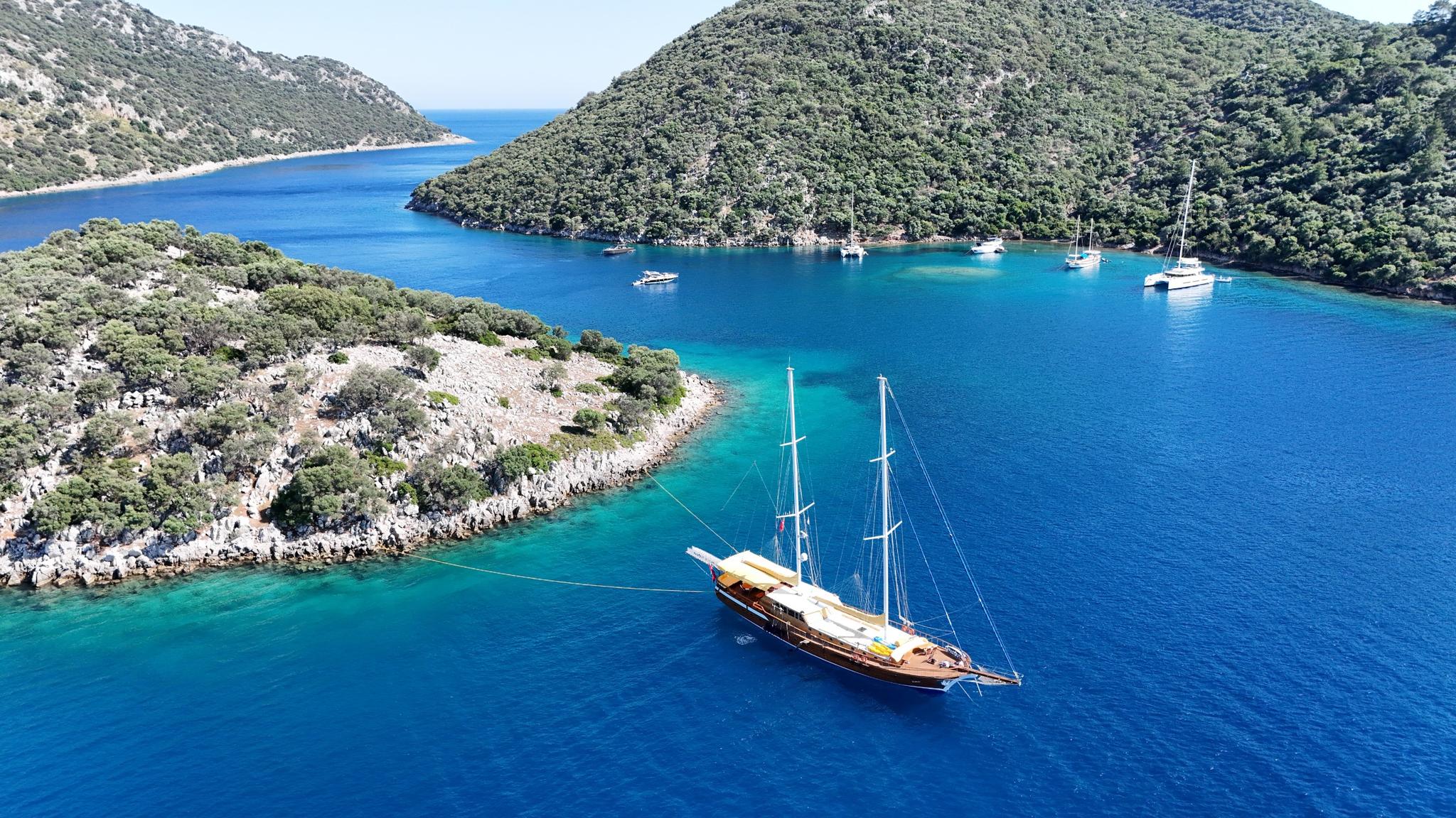aerial view of traditional wooden gulet yacht anchored in crystal clear turquoise Mediterranean bay