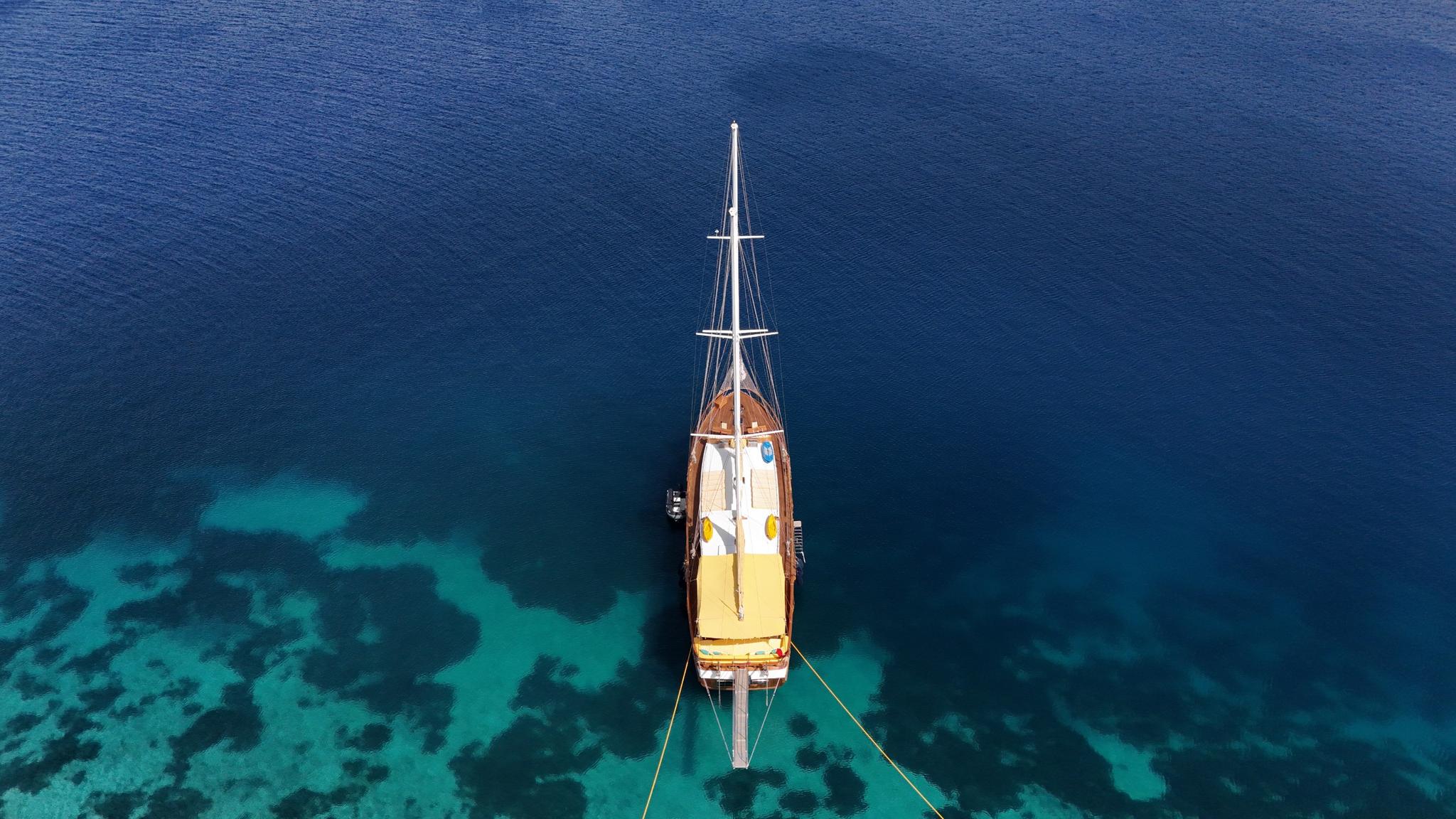 aerial view of wooden gulet yacht anchored in crystal clear turquoise waters