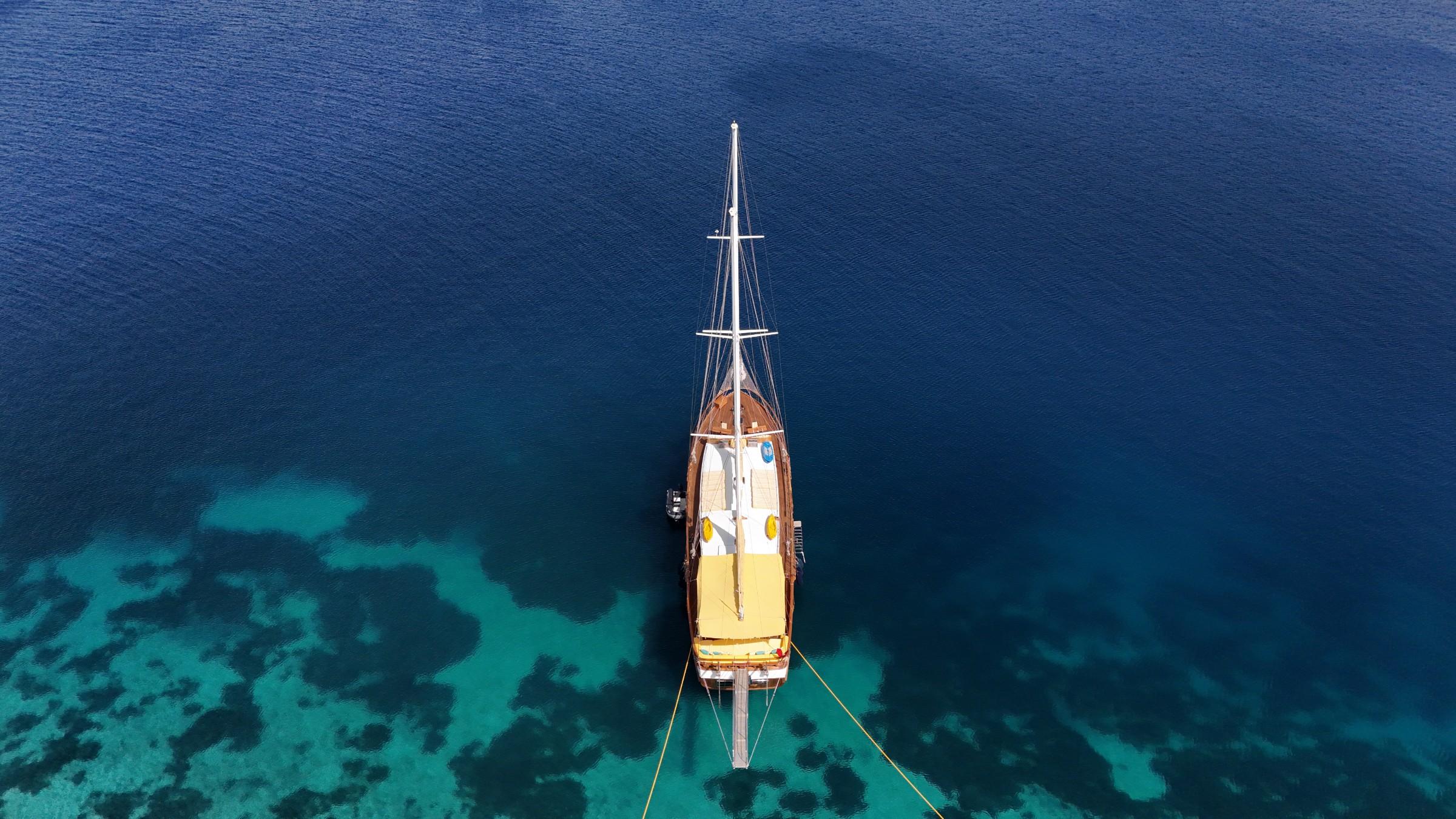 aerial view of wooden gulet yacht anchored in crystal clear turquoise waters